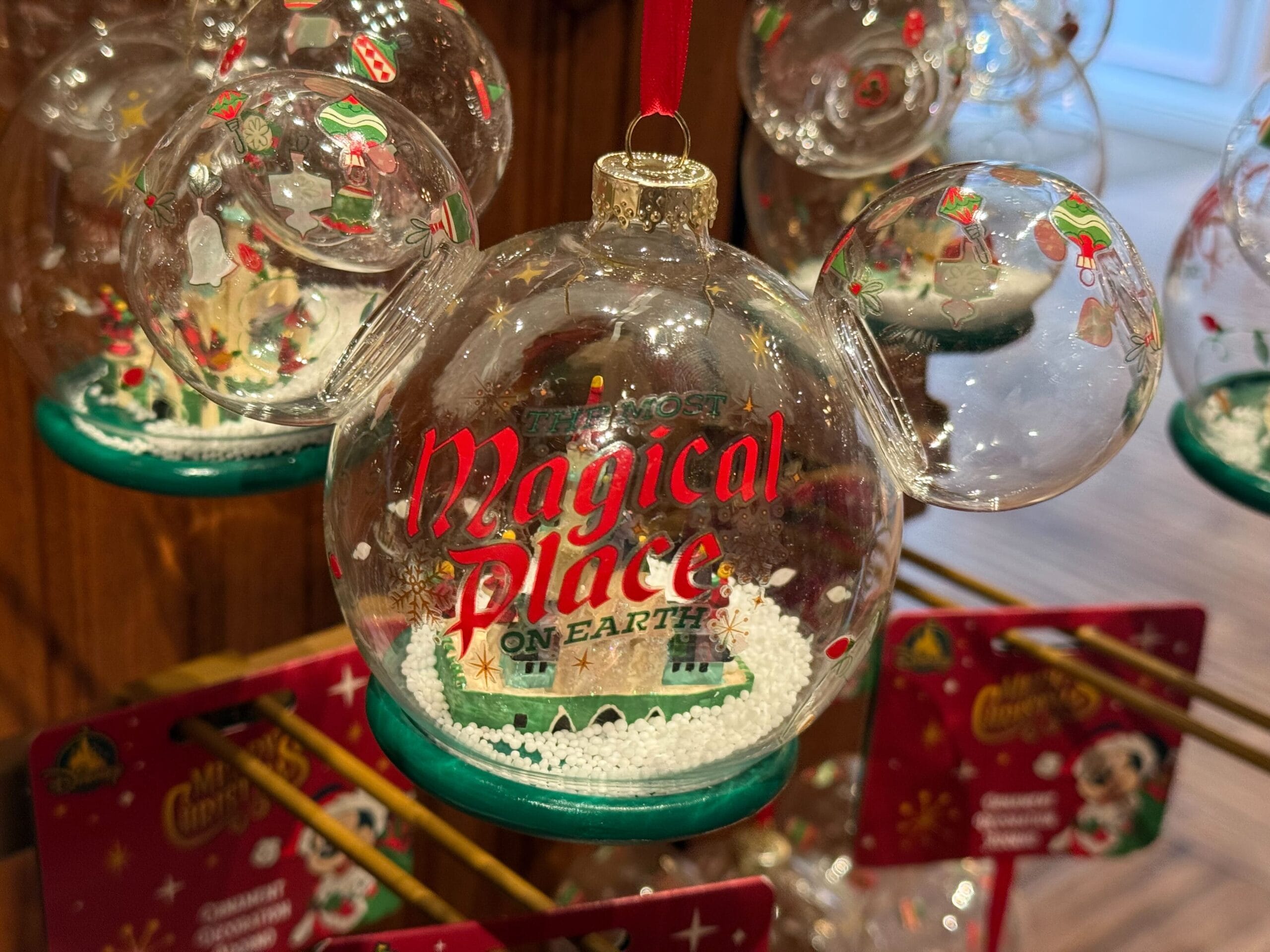 A clear Mickey Mouse-shaped ornament from the 2025 Disneyland Christmas merchandise features snow and a castle inside.