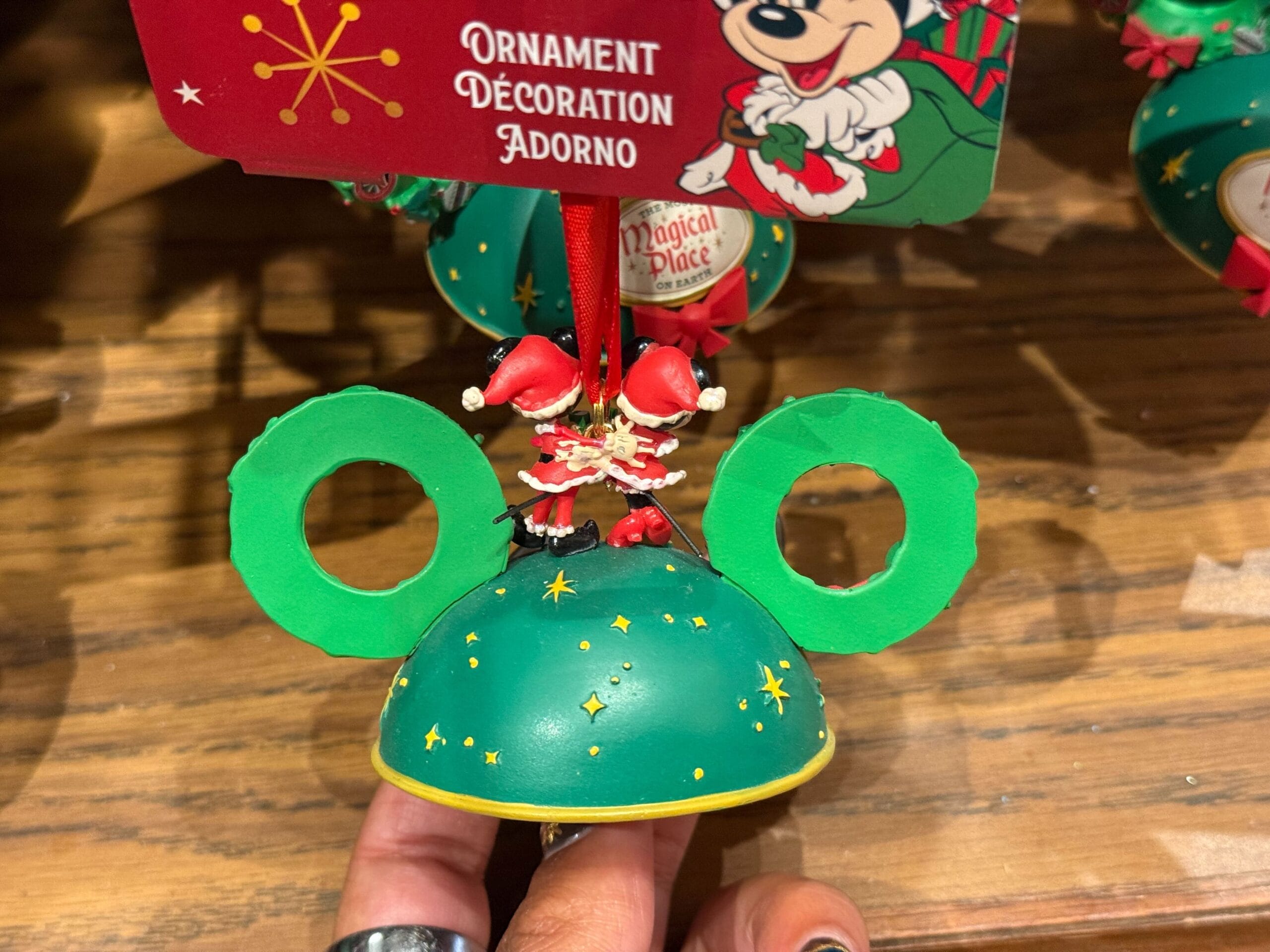Green ornament shaped like Mickey Mouse ears with Santa legs, part of 2025 Disneyland Christmas merchandise.