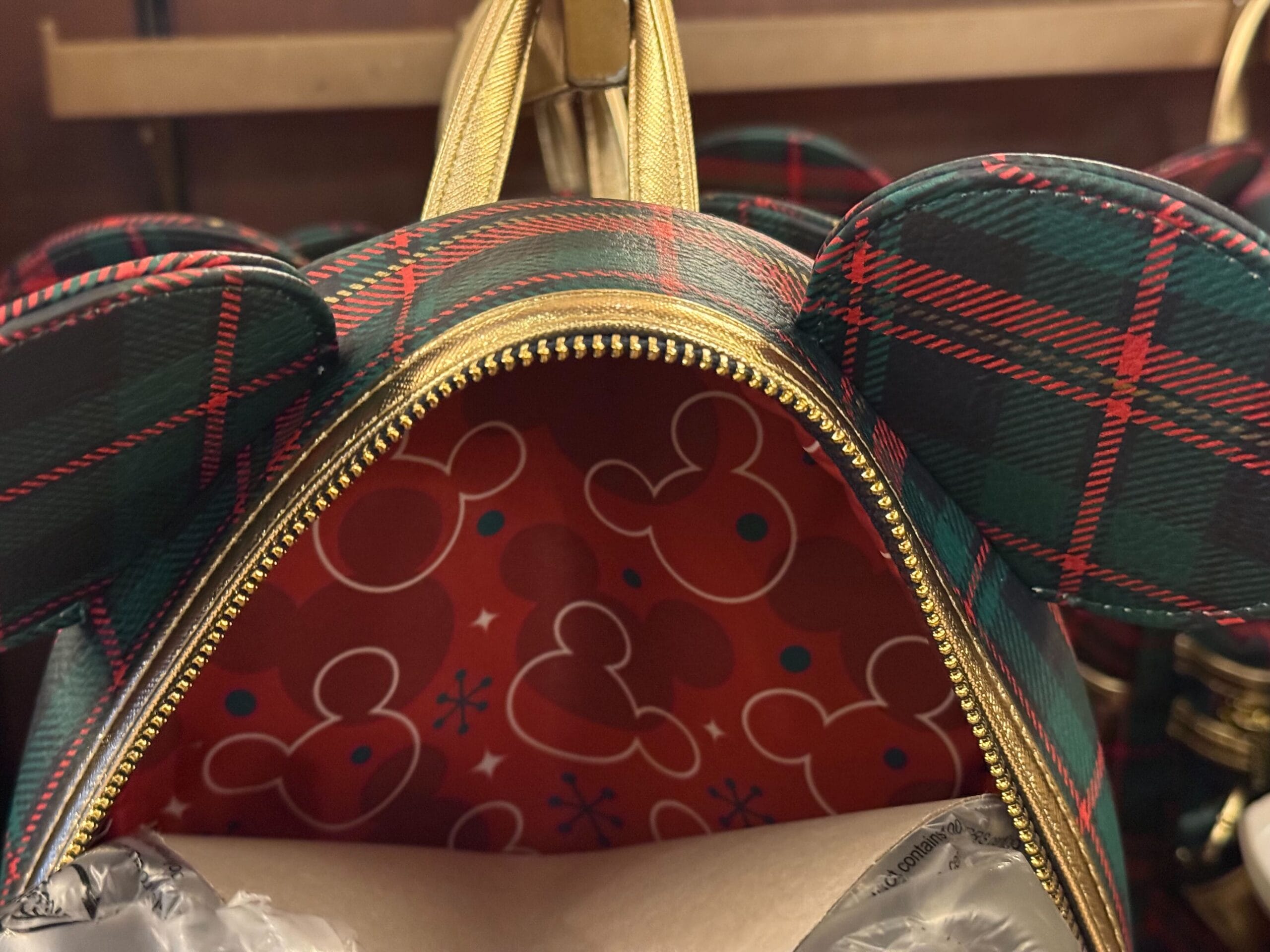 Plaid Christmas Loungefly mini backpack with mouse ears and red Mickey-print lining, spotted at Disneyland Park—no castle in view.