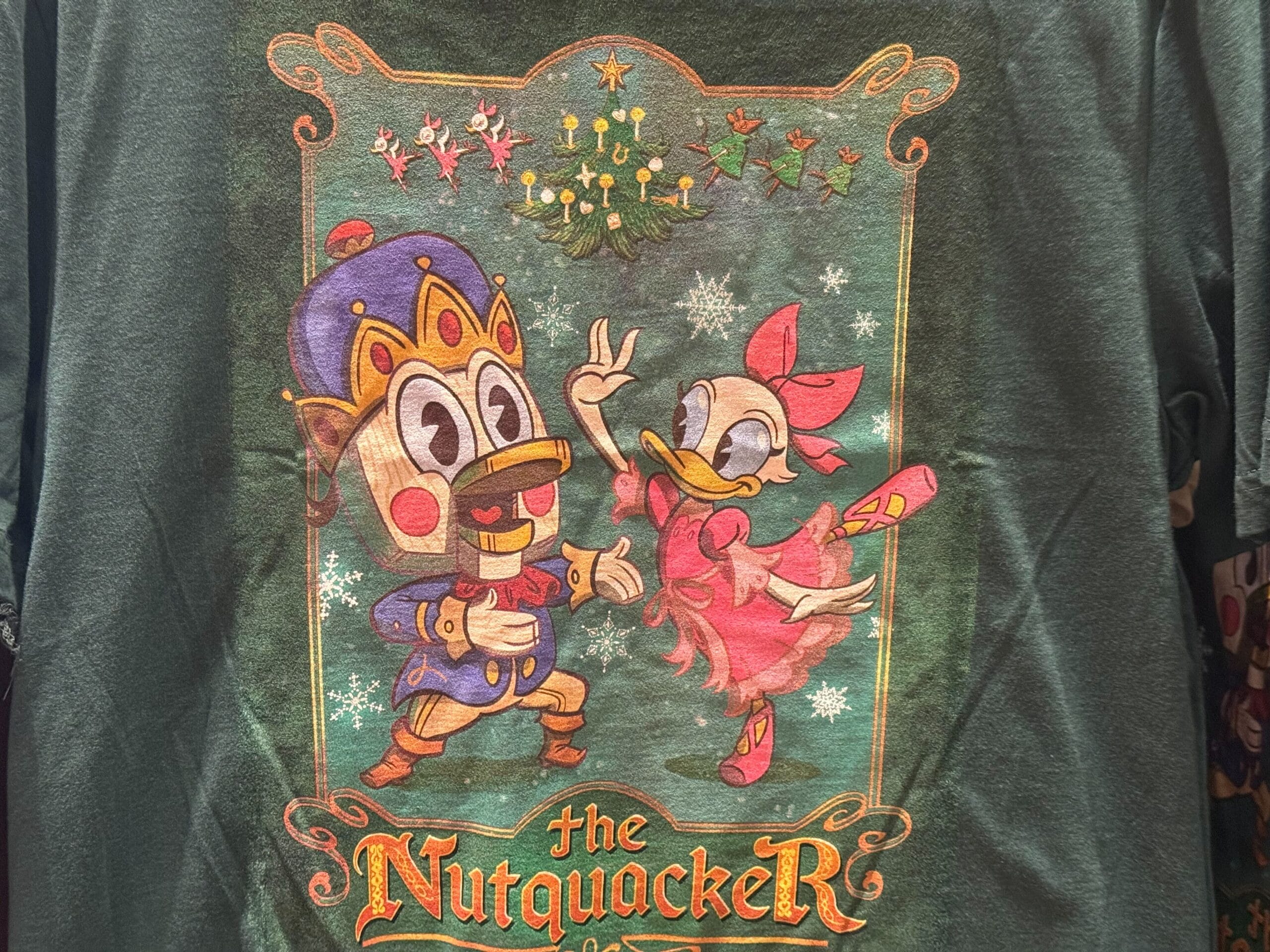 Cartoon nutcracker duck and ballerina duck dance under mistletoe—2025 Disneyland holiday merch, "The Nutquacker." No castle shown.