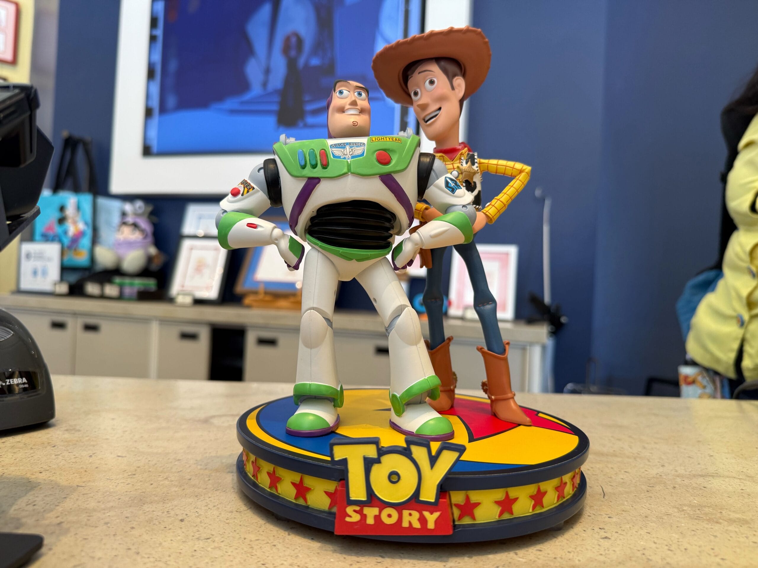 Buzz Lightyear and Woody 30th Anniversary figure stands on a counter with Toy Story logo, like park merch found near Main Street stores.