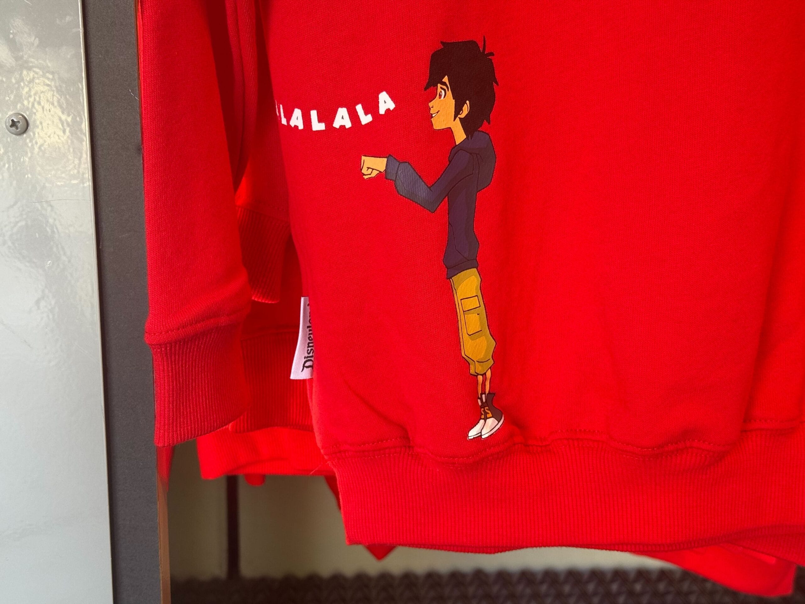 Red sweatshirt featuring a cartoon boy in sneakers and khakis, pointing near "FALALA"
