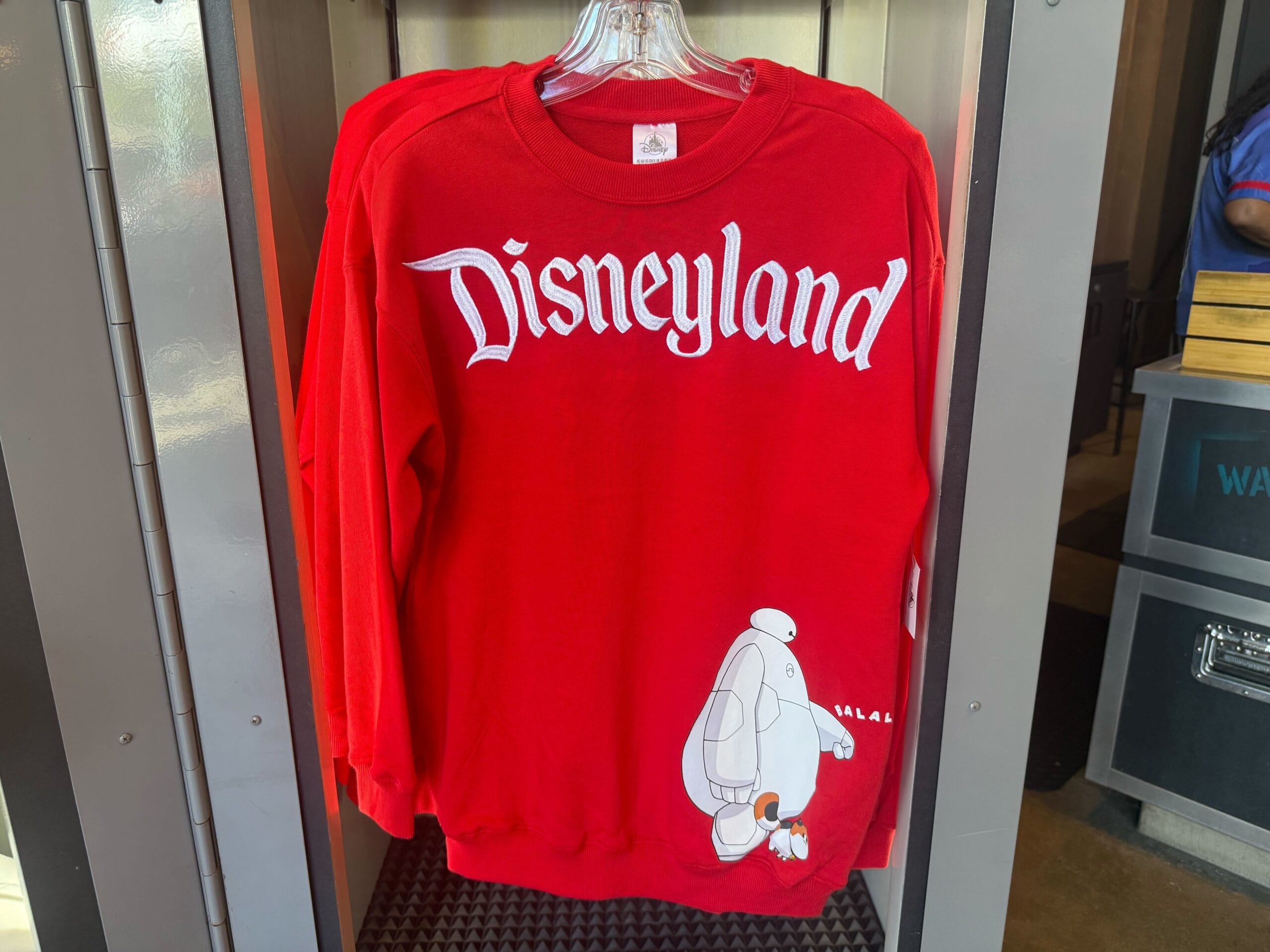 Red Disneyland sweatshirt featuring white lettering and Baymax from Big Hero 6 by the hem, classic park style