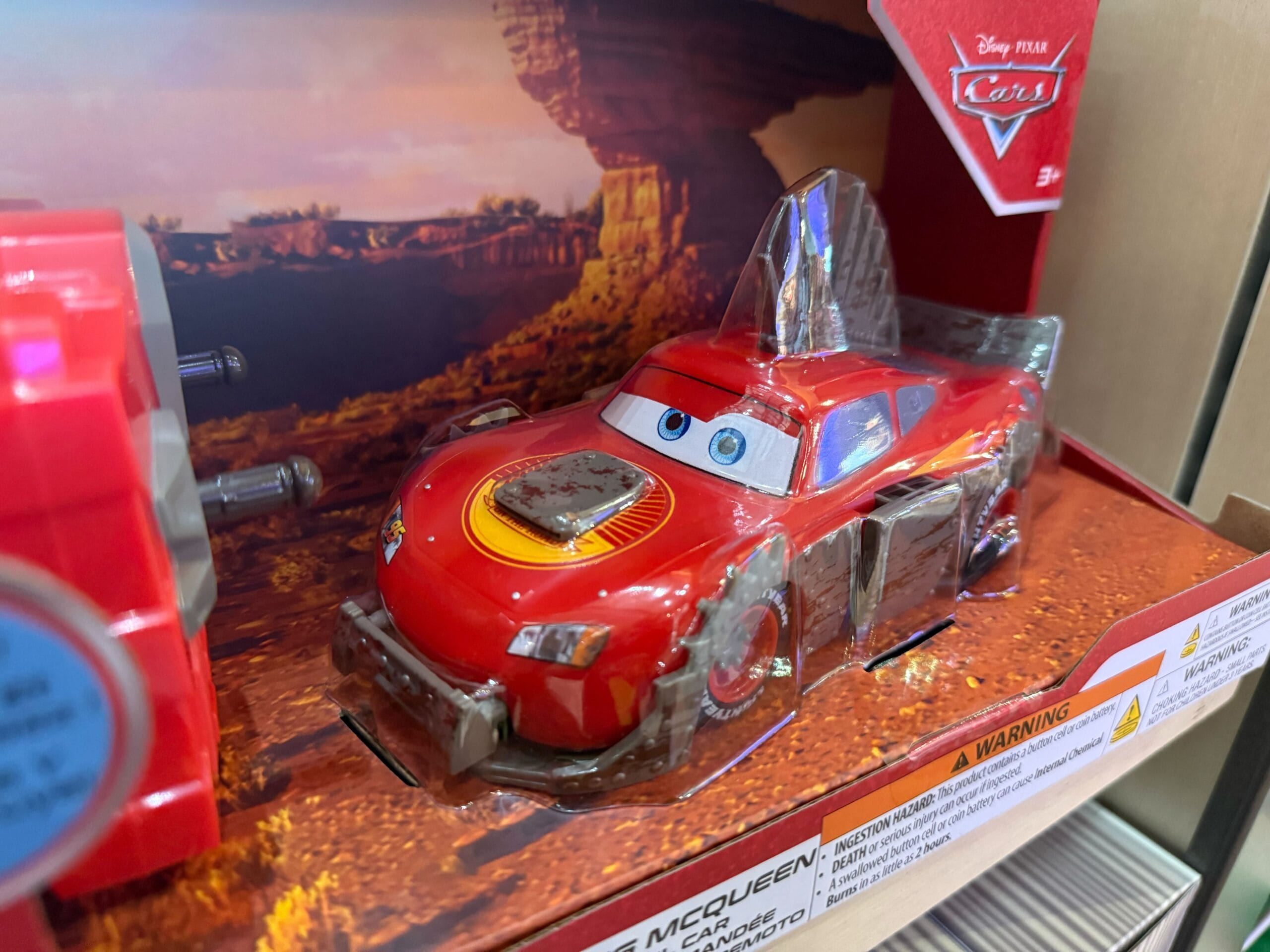 A red Lightning McQueen toy car from Disney Pixar Cars in its packaging, found at a Disneyland Resort shop.