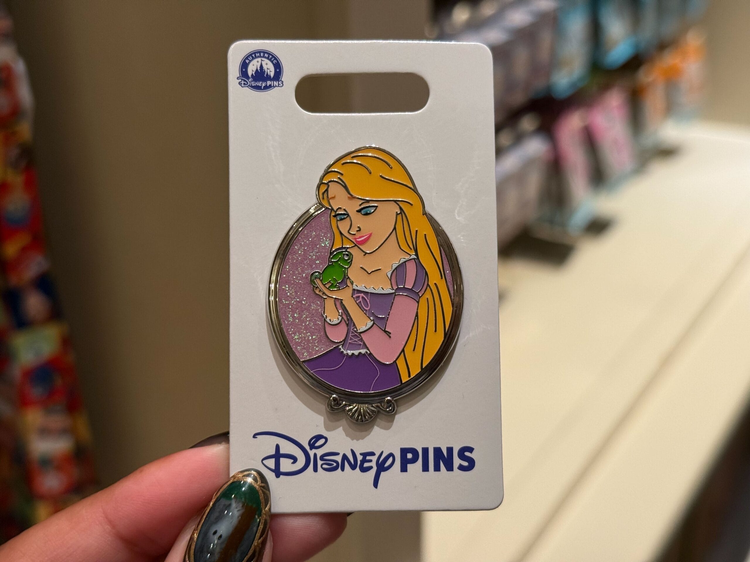 A Disney Princess pin with Rapunzel holding Pascal, her green chameleon, on a glittery pink background, reminiscent of park exclusives.
