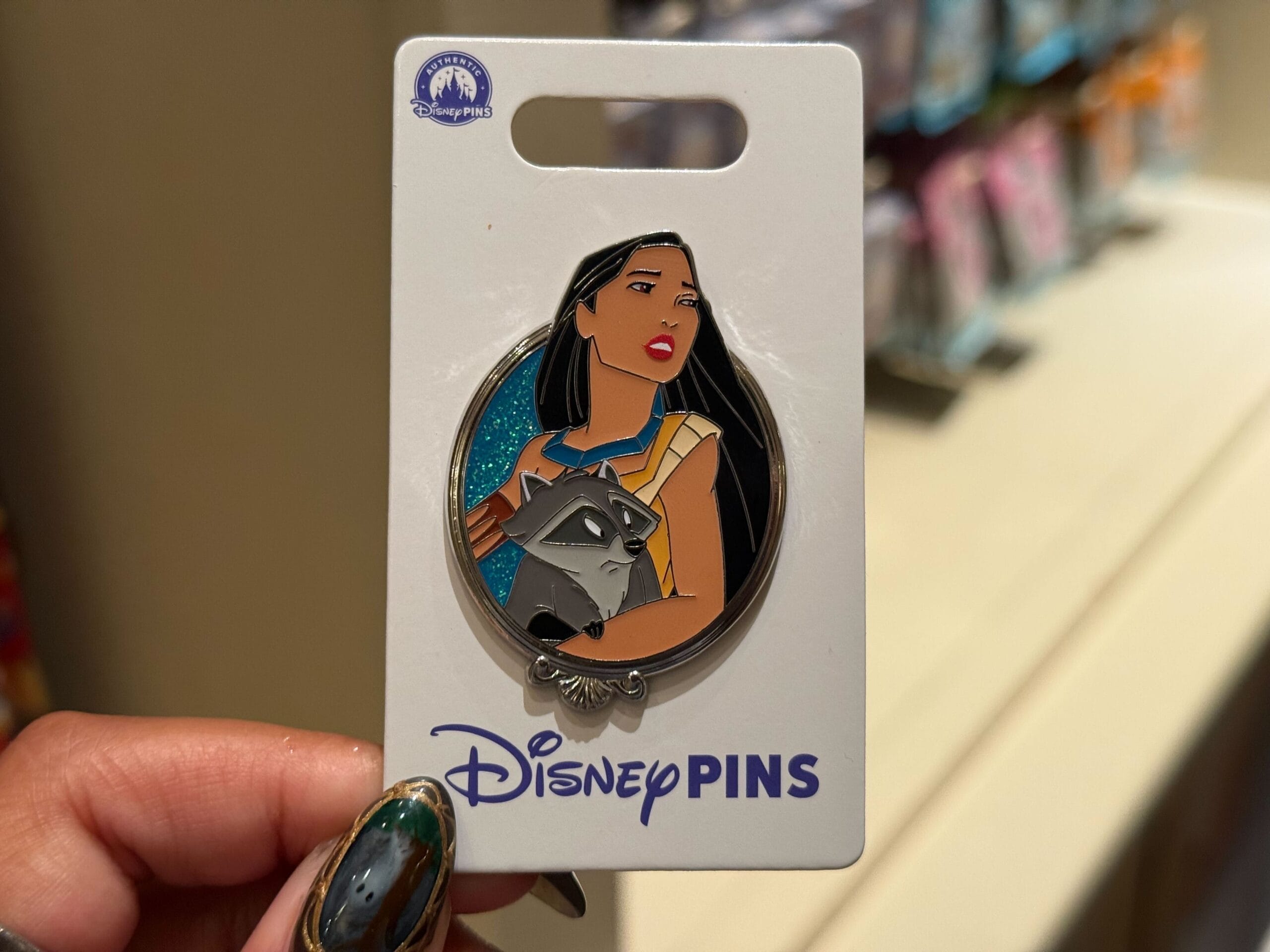 A Disney Princess Pin of Pocahontas holding Meeko the raccoon, shown on a Disney Pins card from one of the Disney Parks.