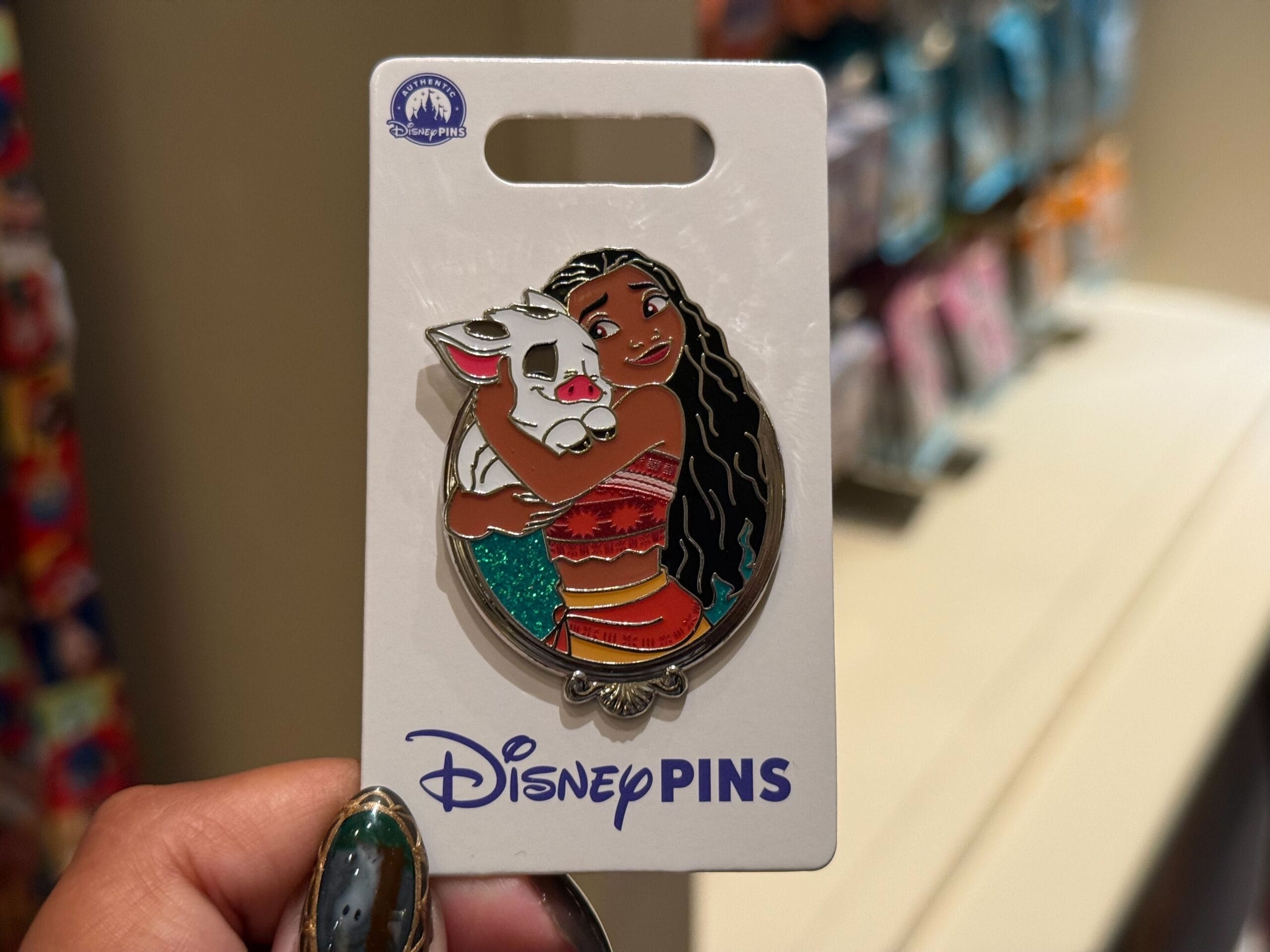 Moana hugs Pua on a Disney Princess pin, displayed on a backing card found in many global Disney Parks merchandise shops.