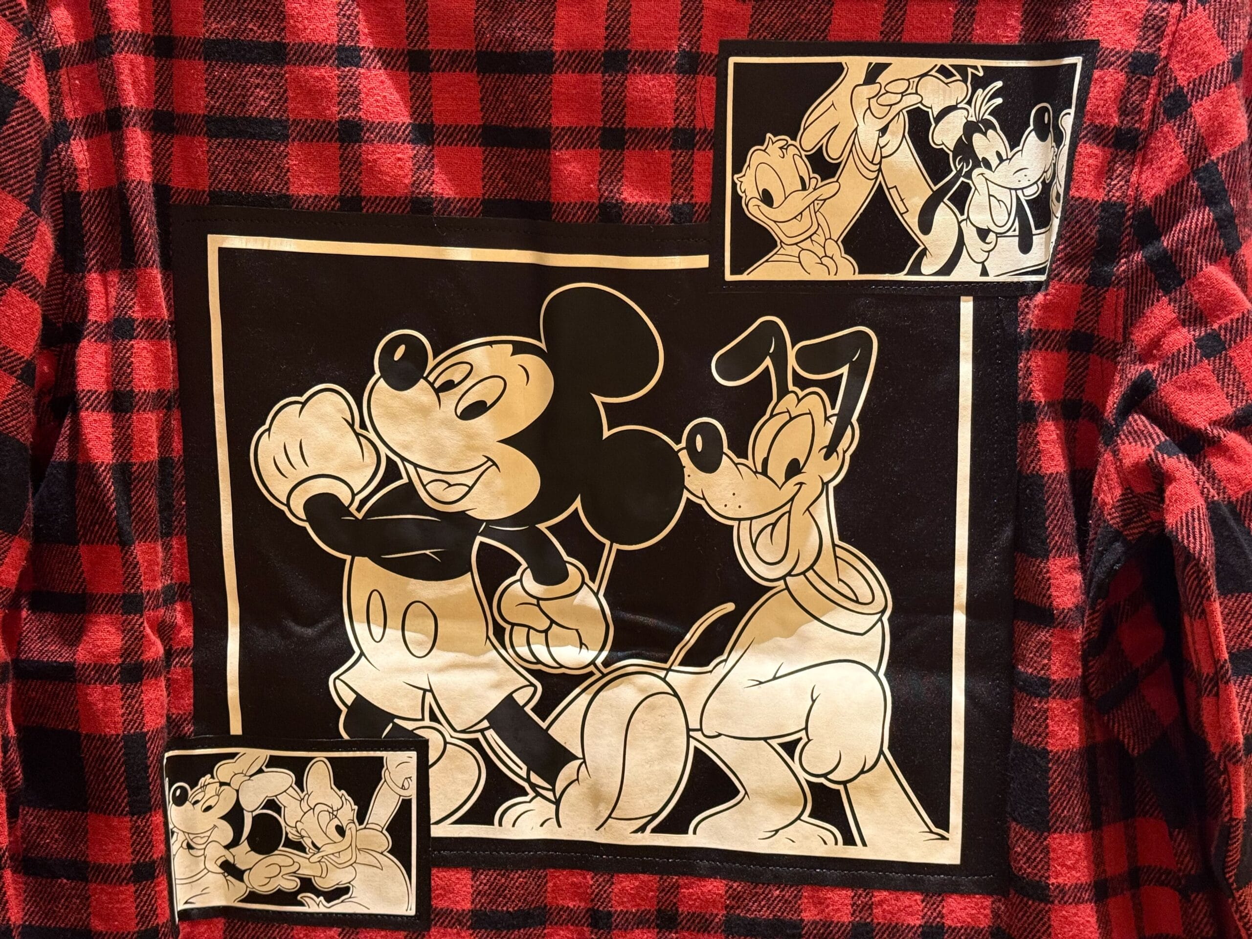 Red plaid shirt with black and white Disney characters on the back, echoing classic park merch—ideal for Disneyland fans.