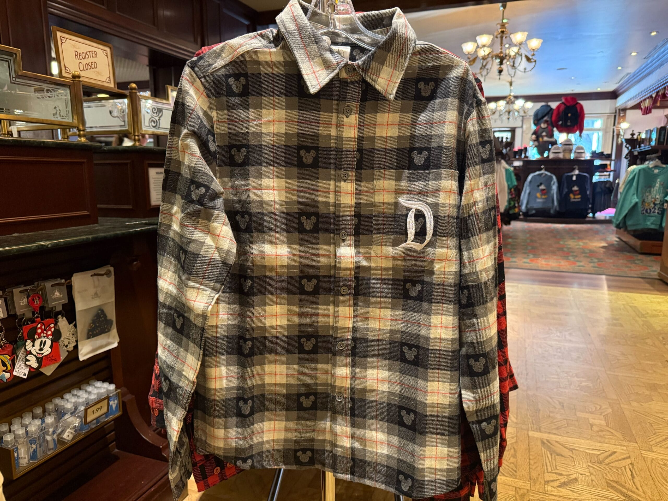 Plaid button-up shirt with white "D" and Mickey heads—classic Disneyland merch, iconic like Sleeping Beauty Castle vs. Cinderella’s.