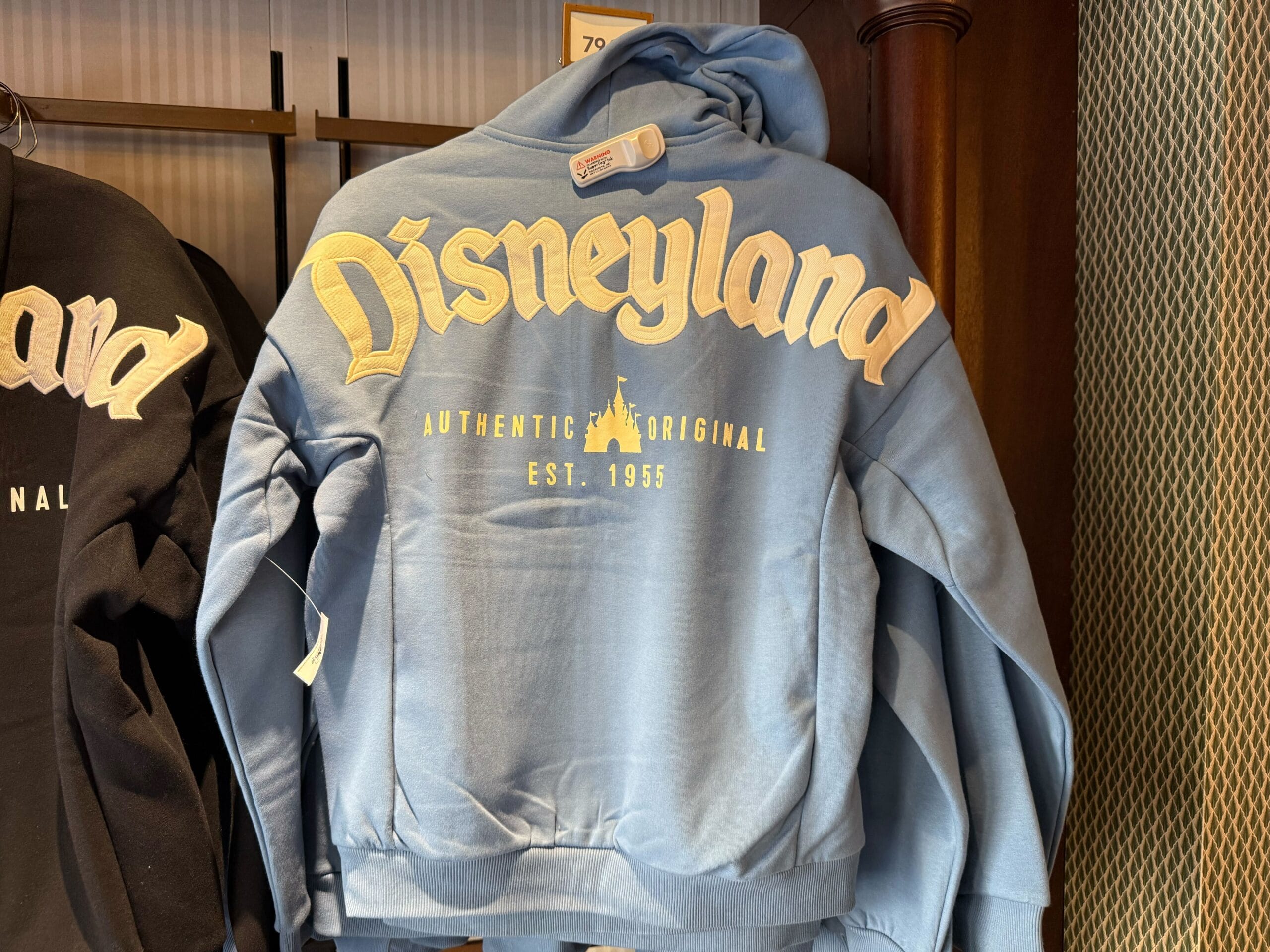 Light blue Disneyland hoodie with yellow “Disneyland Authentic Original Est. 1955” text, classic park merch; no castle shown.