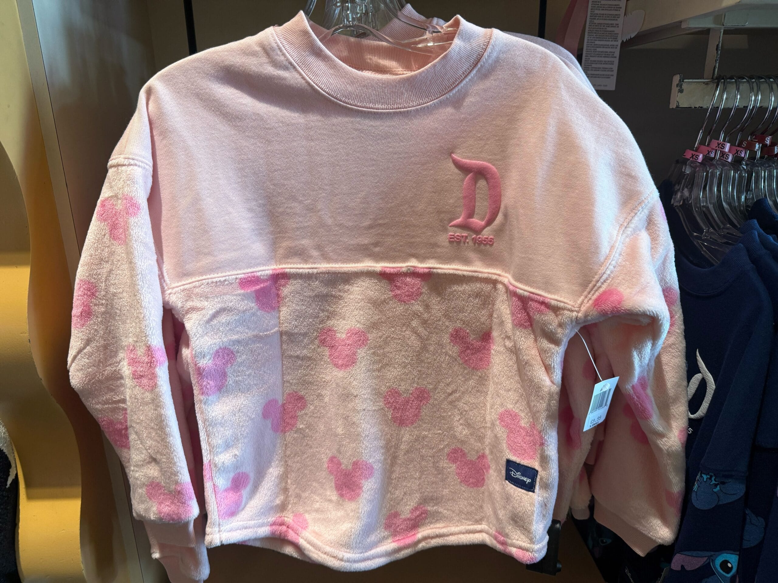 Light pink sweatshirt with pale pink Mickey Mouse heads, official Disneyland park merch since 1955—no castle featured here.