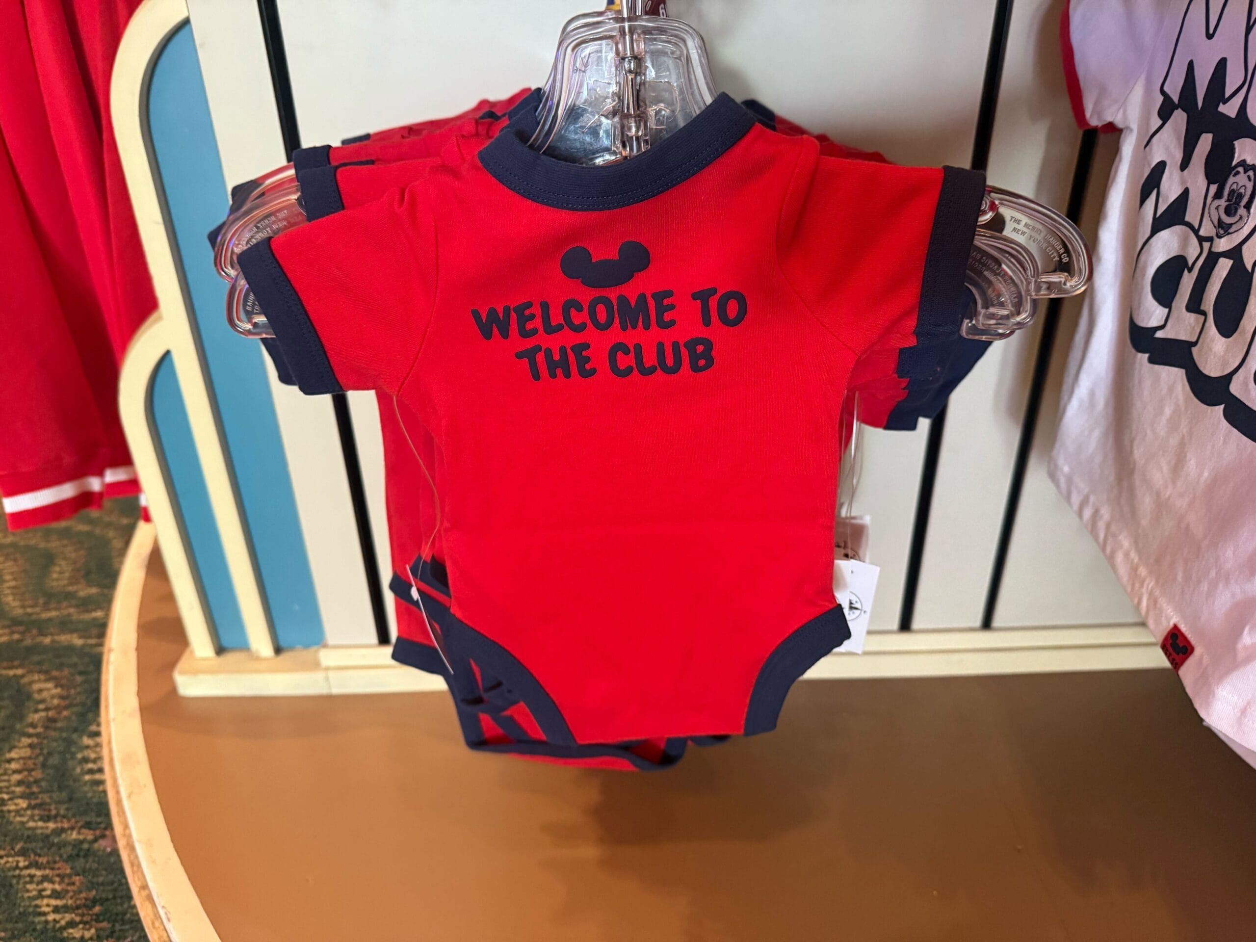 Red baby onesie with navy trim and "Welcome to the Club"—a cute pick from Disney Parks, perfect for Mickey Mouse Club fans.