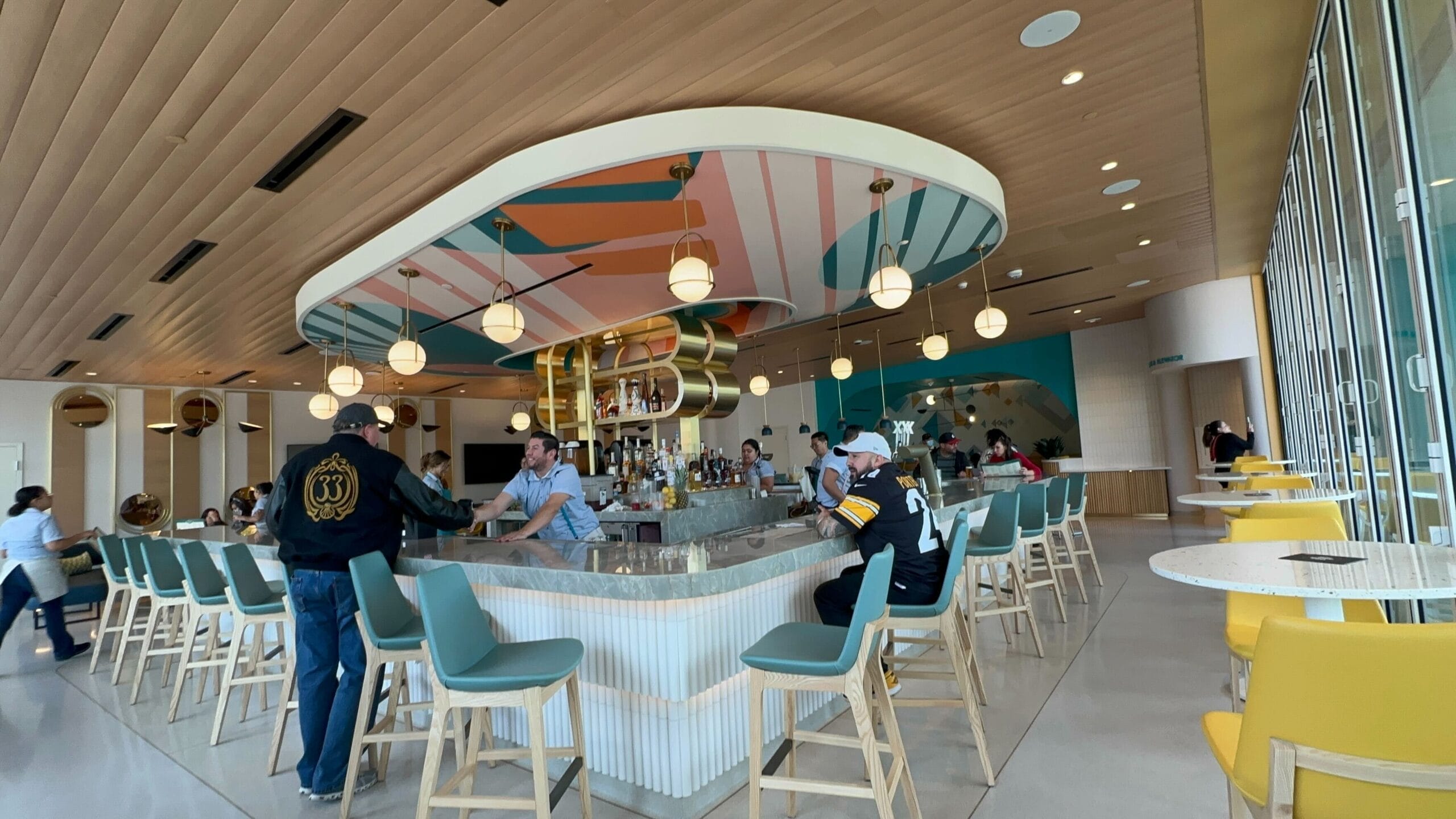Guests mingle at a vibrant bar with globe lights in open Downtown Disney, no view of any Disney castle compared to park icons.
