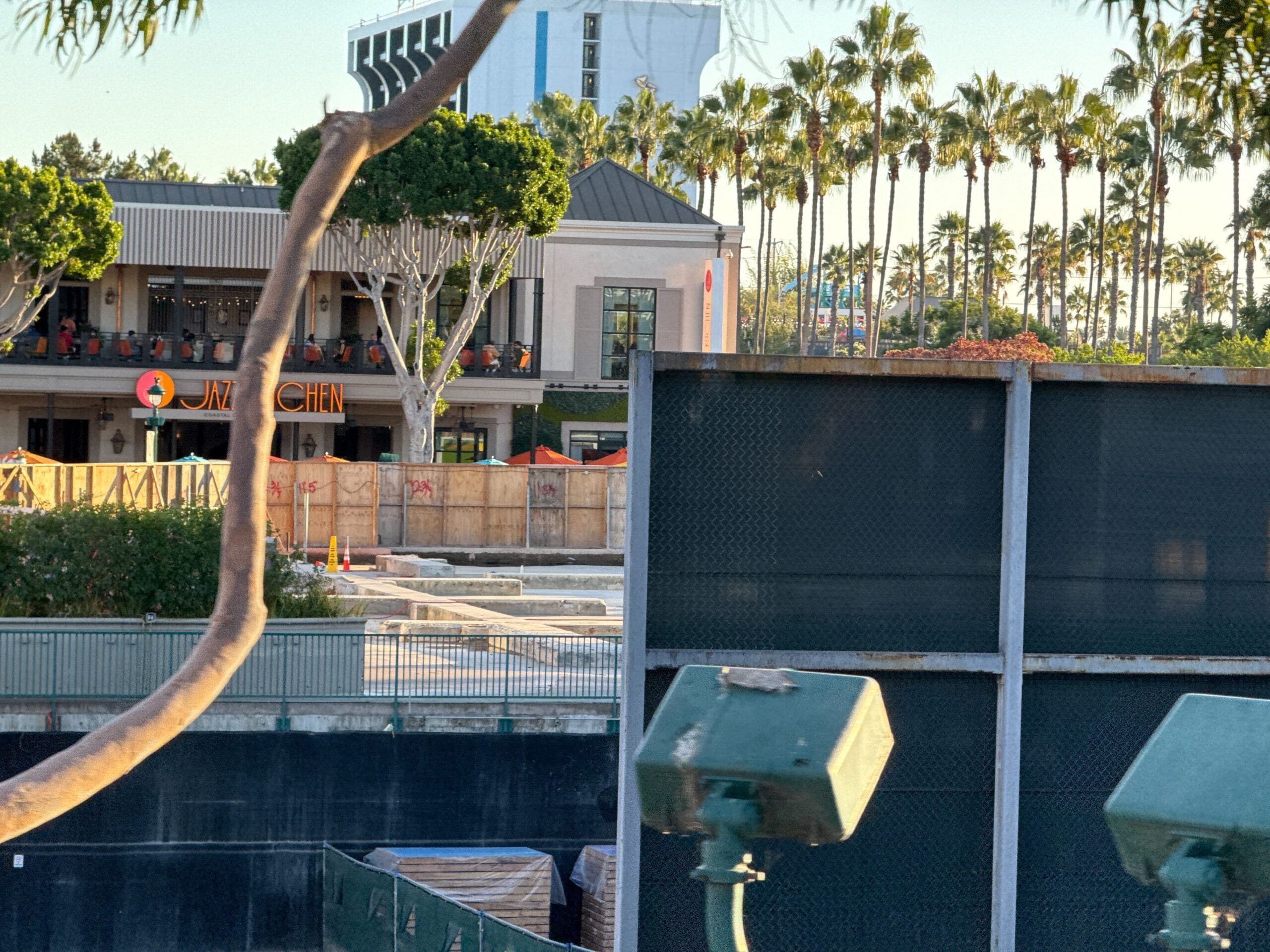 A construction site with barriers near Juju Kitchen and palm trees, close to Downtown Disney, no castle like those in Disney parks.