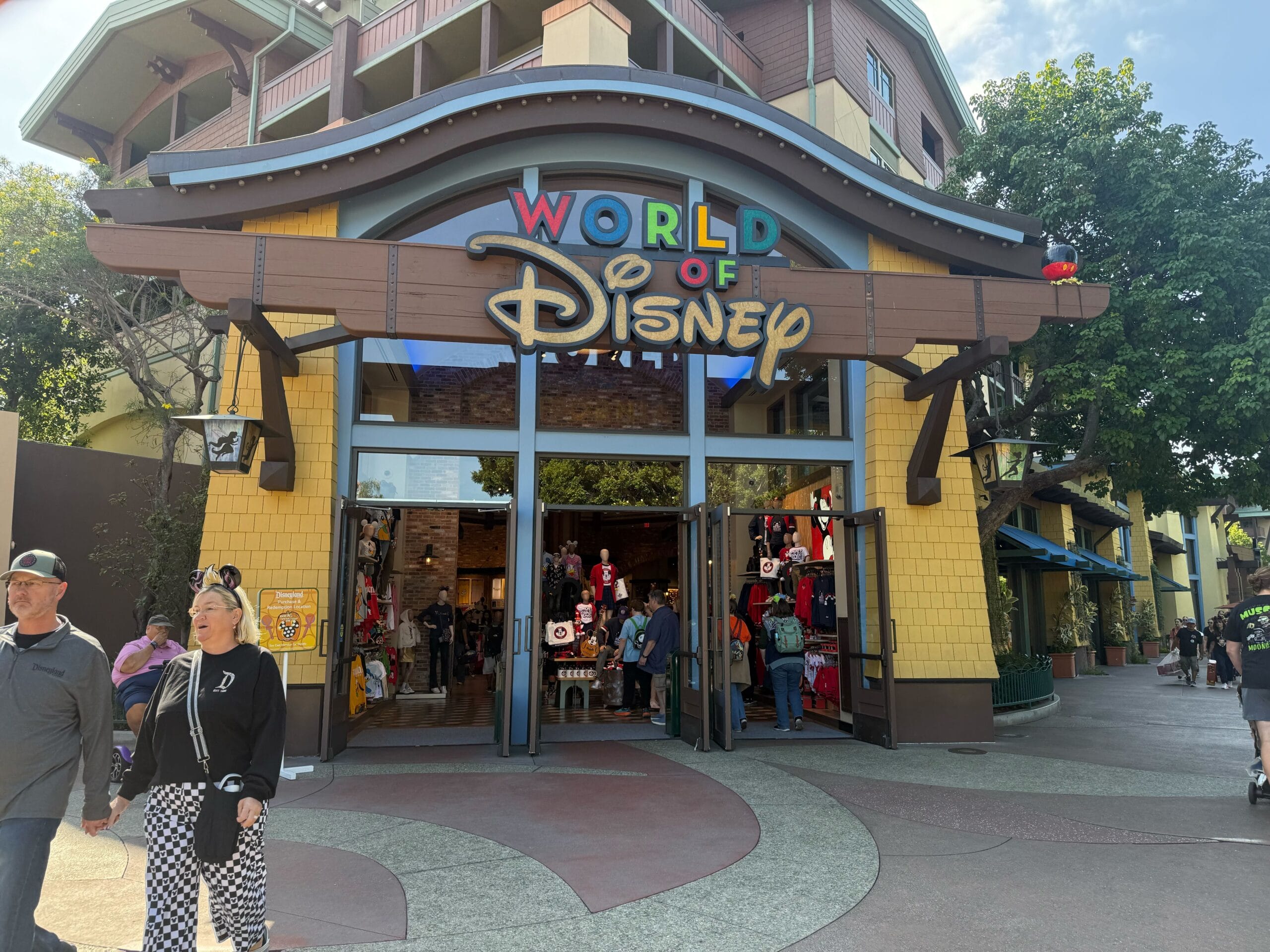 Guests stroll by the vibrant Downtown Disney entrance, some with sleek stainless steel wine tumblers—no castle in view here.