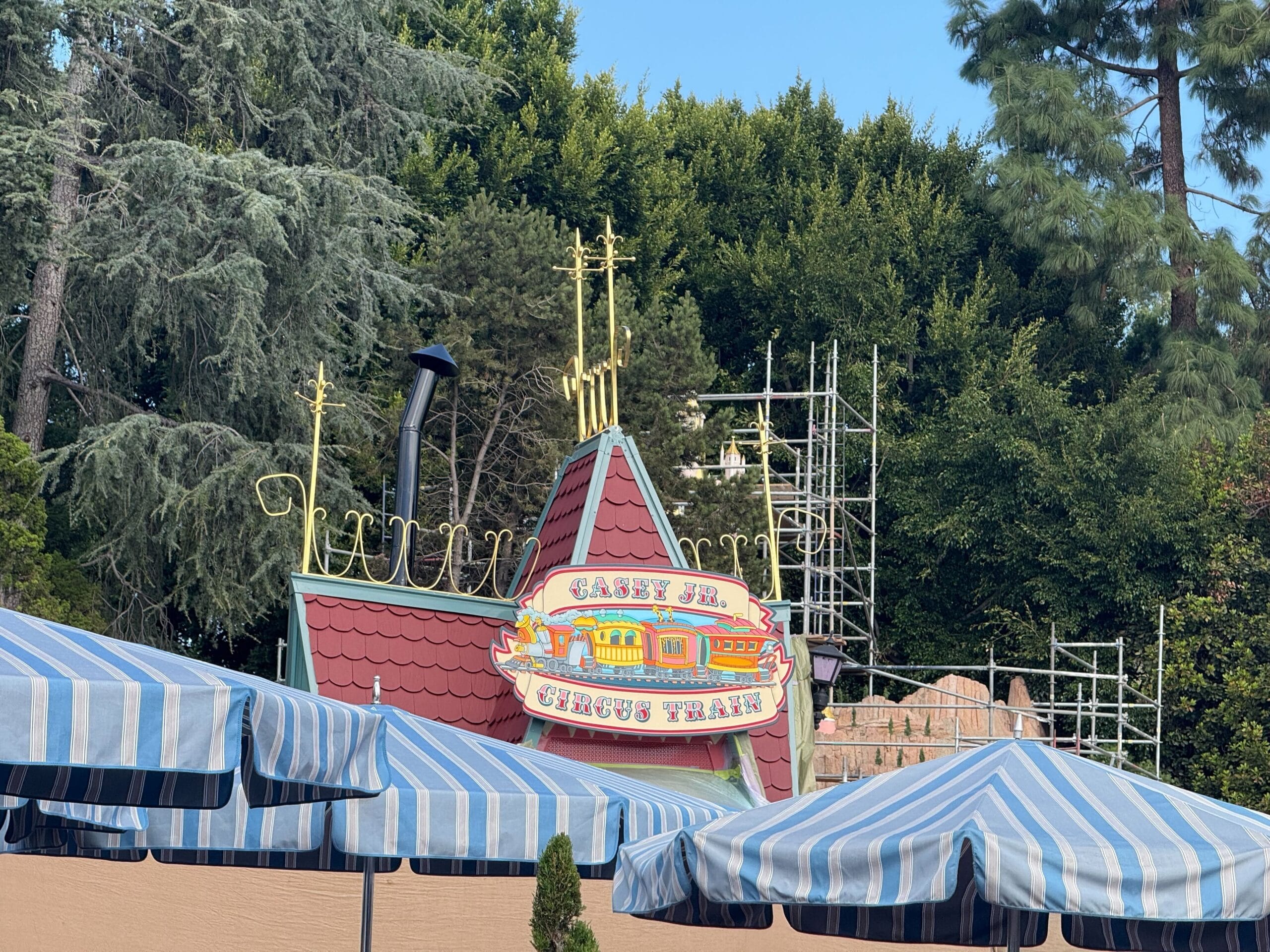 Casey Jr. Circus Train sign at Disneyland, with scaffolding and striped canopies visible during refurbishment work
