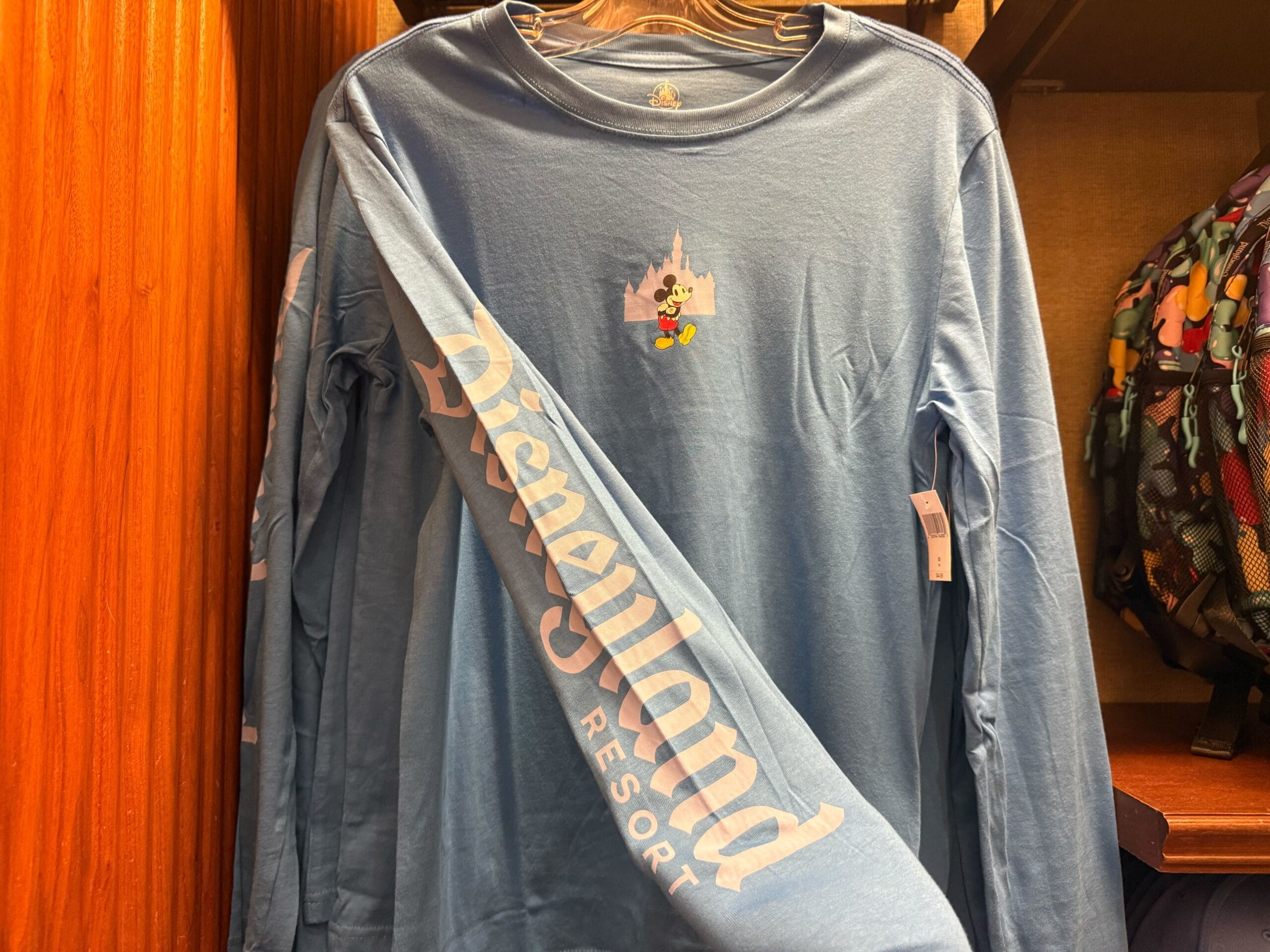 Disneyland blue long-sleeve shirt with Mickey Mouse and a castle graphic on the chest, resembling Sleeping Beauty Castle at Disneyland.