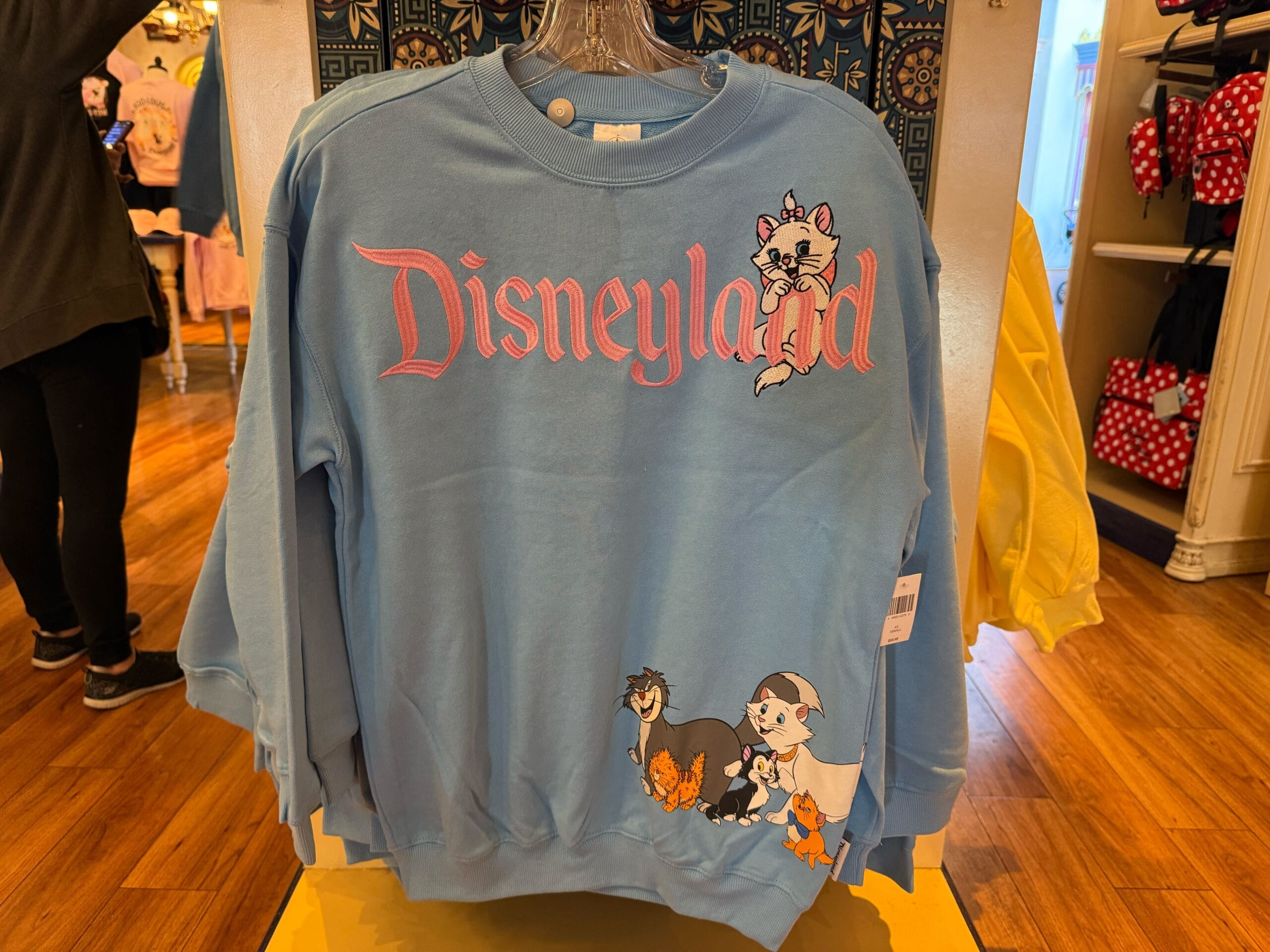 Blue Disneyland sweatshirt featuring pink lettering and Disney’s Aristocats, like ones seen at Disney Parks