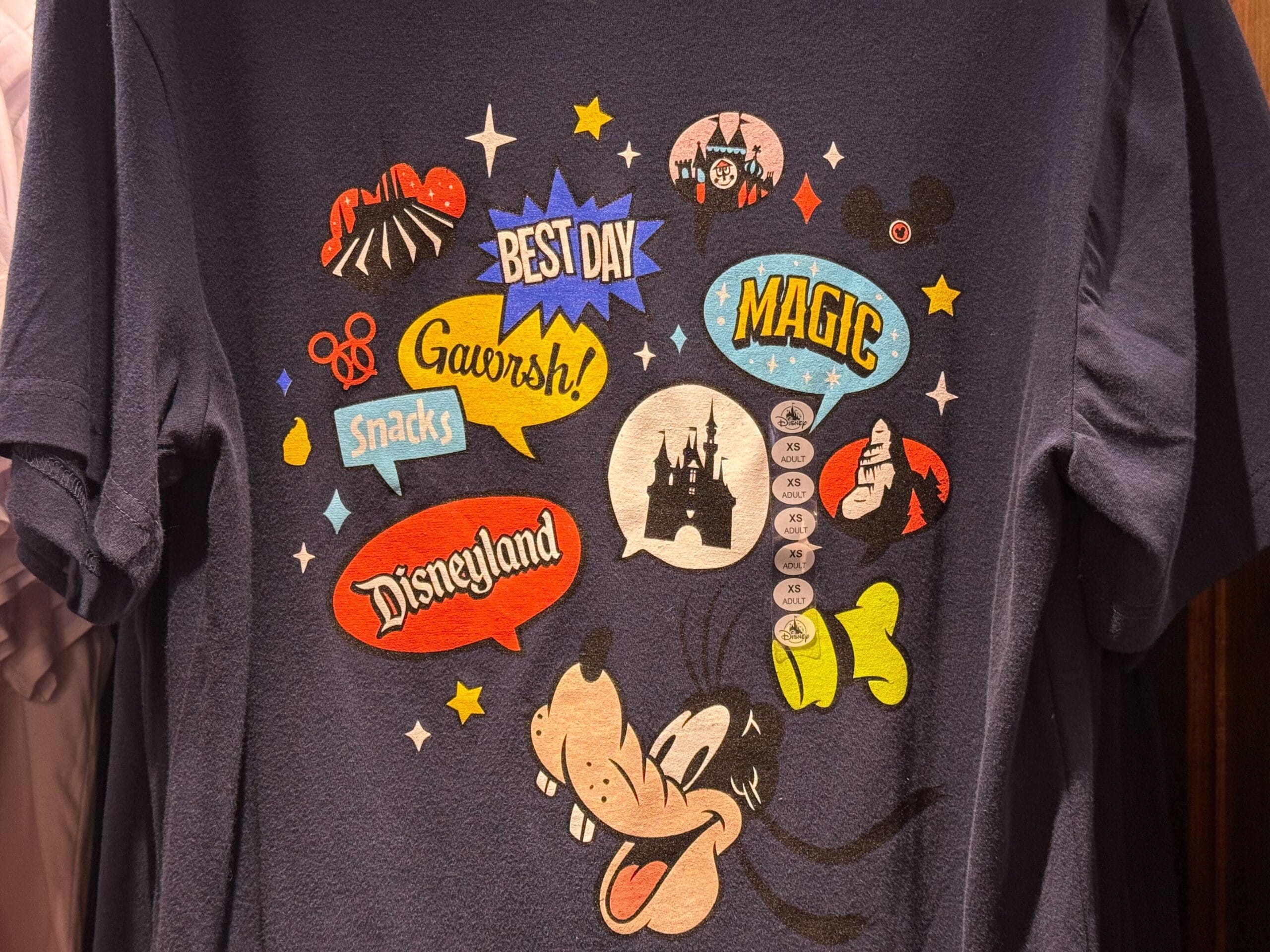 Navy shirt featuring Goofy, speech bubbles, and a castle resembling Disneyland Anaheim