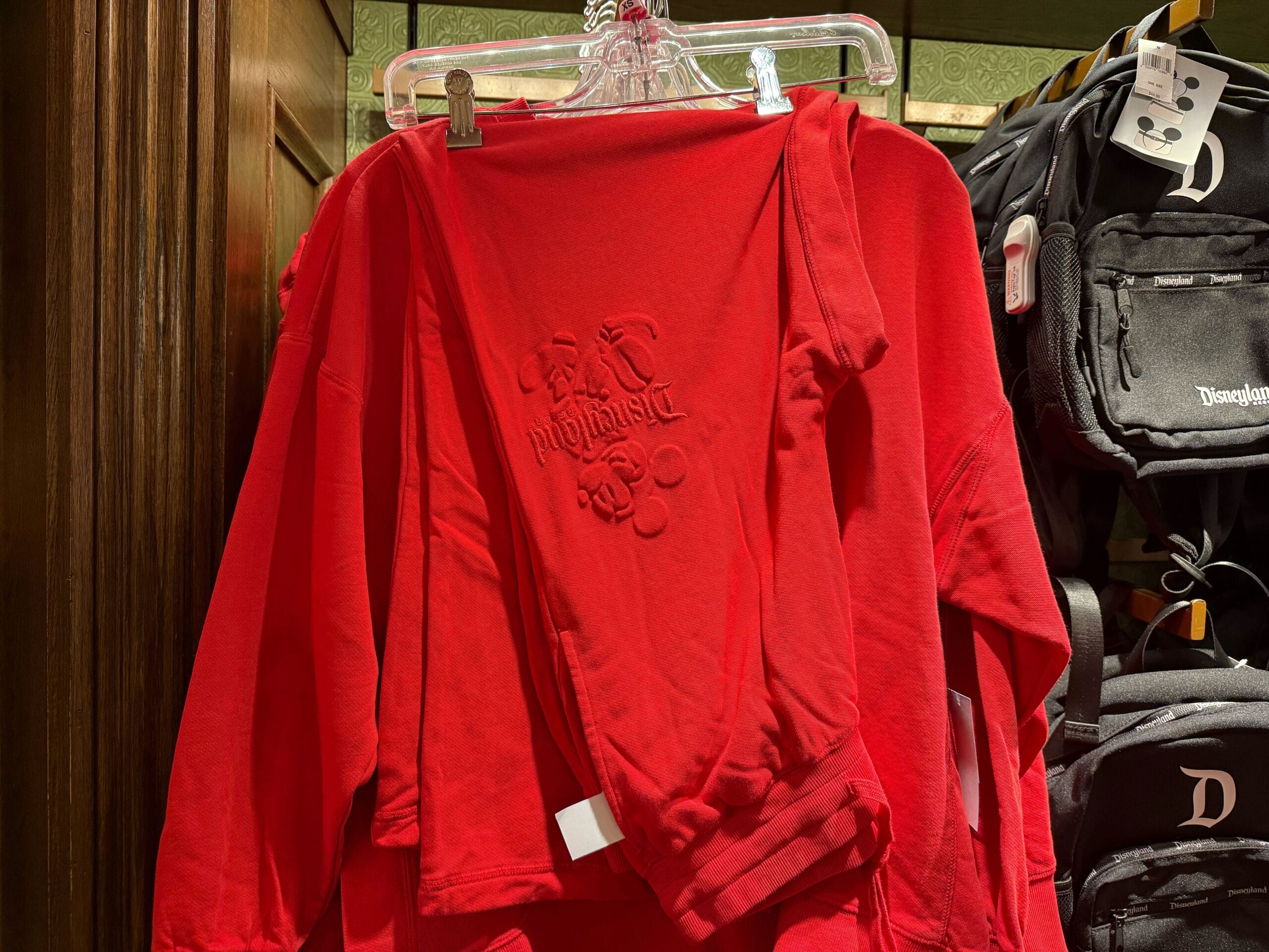 Red "Fantasmic!" sweatshirt on display with Disneyland sweaters and black backpacks