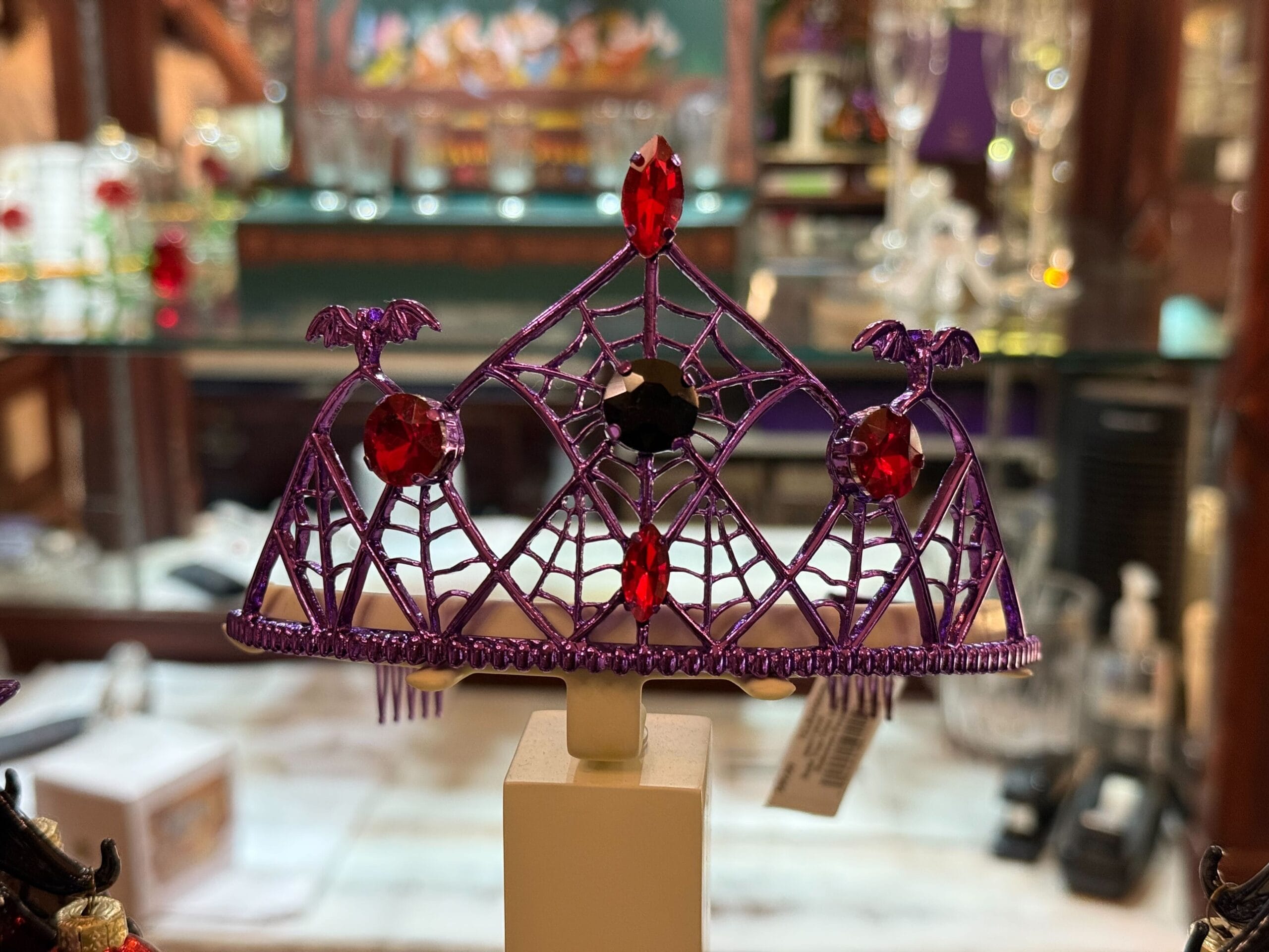 A purple Halloween tiara with bats, red gems, and spiderwebs on display at Disneyland
