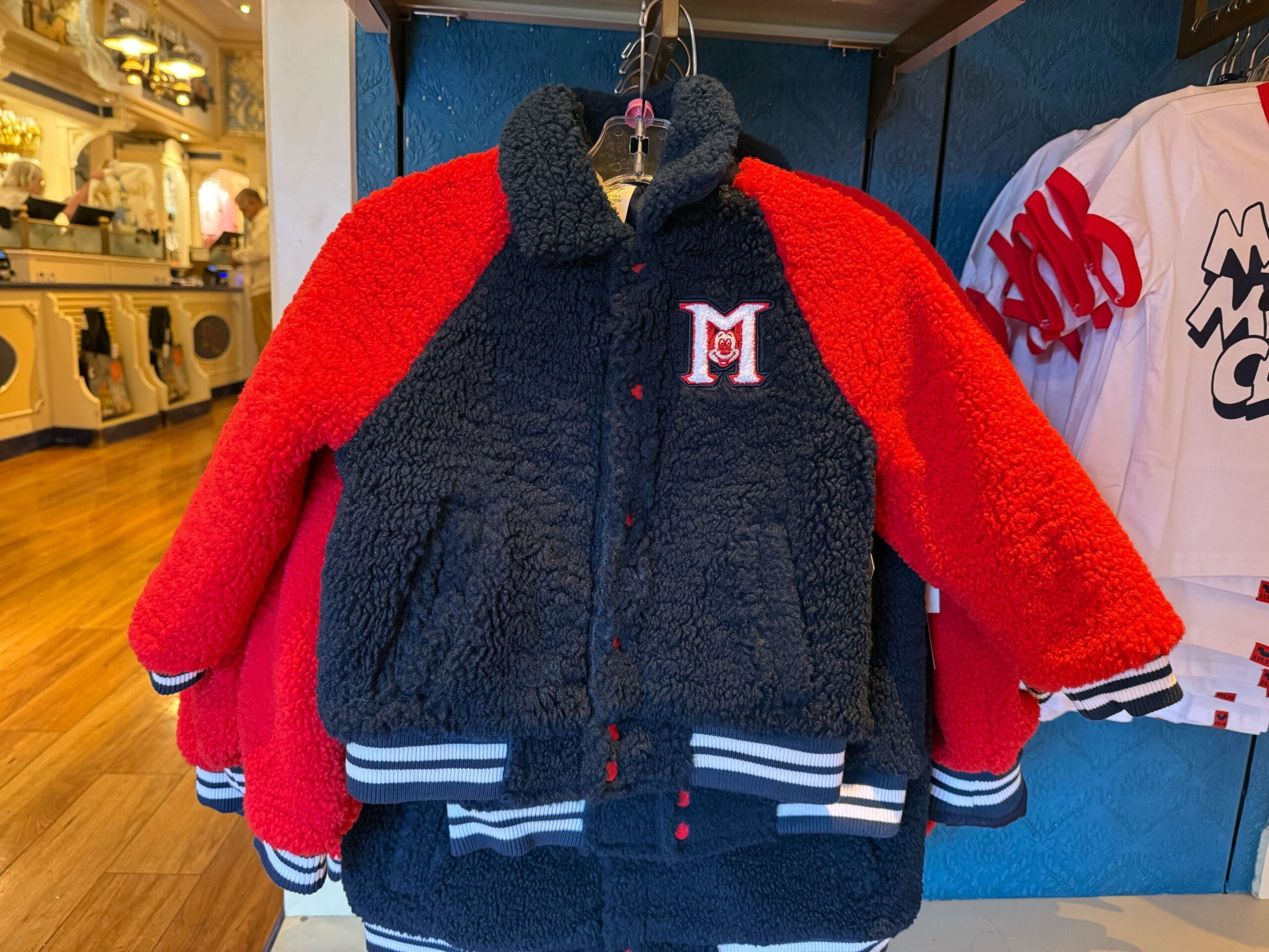A fuzzy navy and red varsity jacket for kids with an "M" patch, inspired by classic Mickey Mouse Club merchandise.