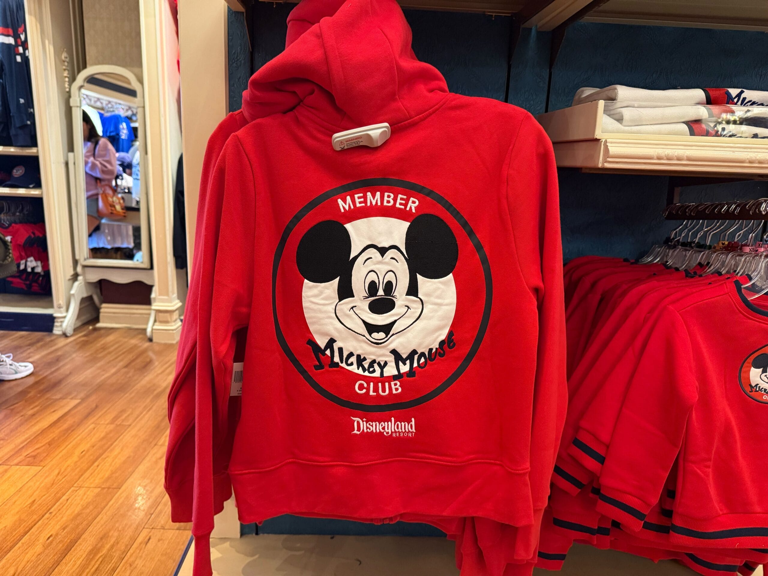 Red hoodie featuring a large "Member Mickey Mouse Club" logo, celebrating the 70th anniversary at a Disneyland store.