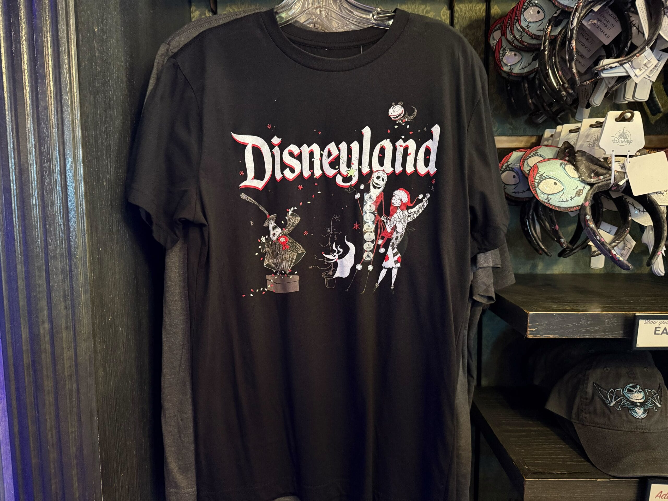 Black Disneyland shirt with Jack, Sally, and the Mayor from The Nightmare Before Christmas on display in a Disney park store.