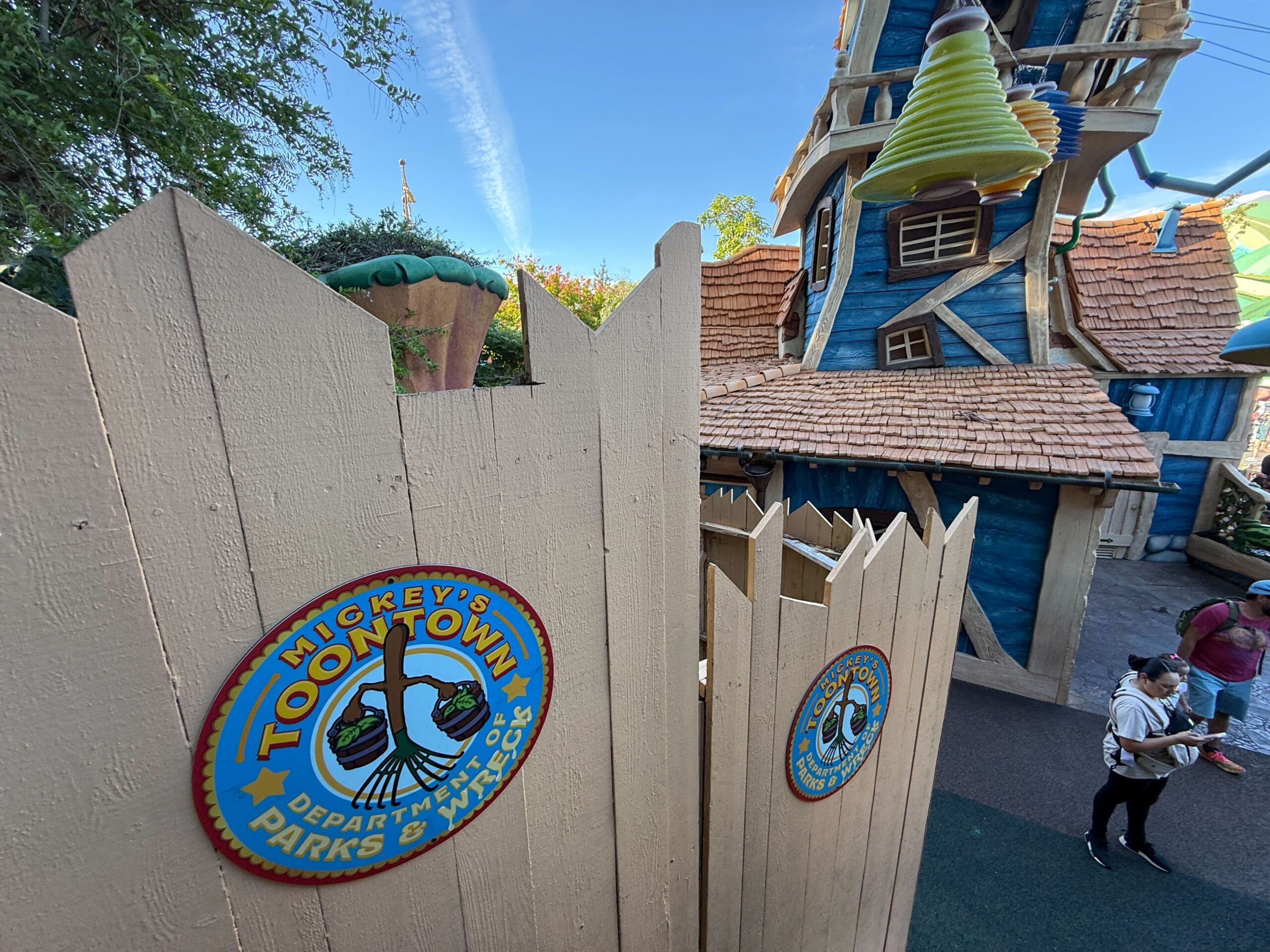 Mickey's Toontown" signs on wooden construction walls, a blue cartoon house, and guests, all at Disneyland—not a castle scene.