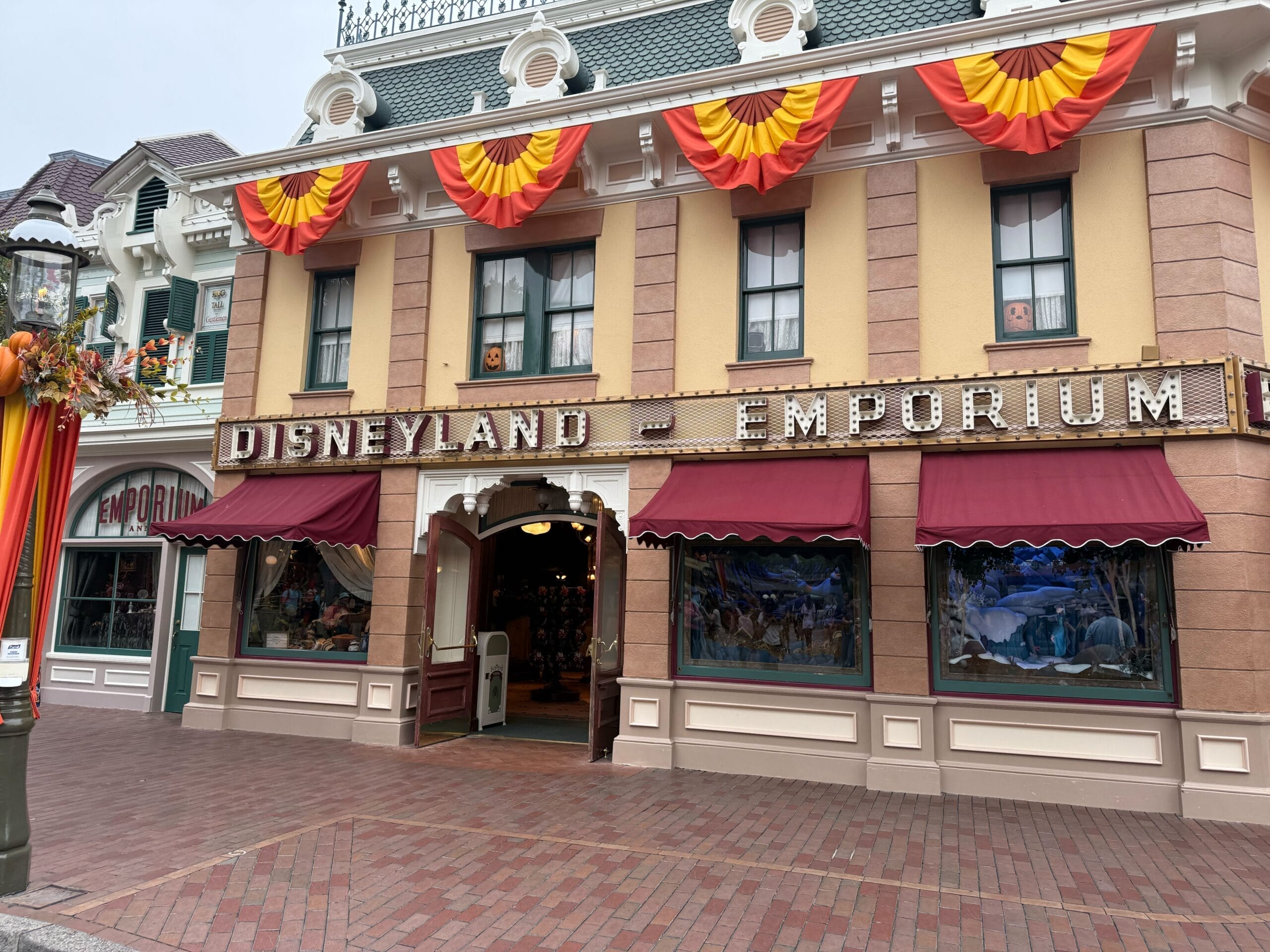 Disneyland Emporium with red and yellow bunting, big windows, and a Winter Blue Loungefly Backpack, no castle in this scene.