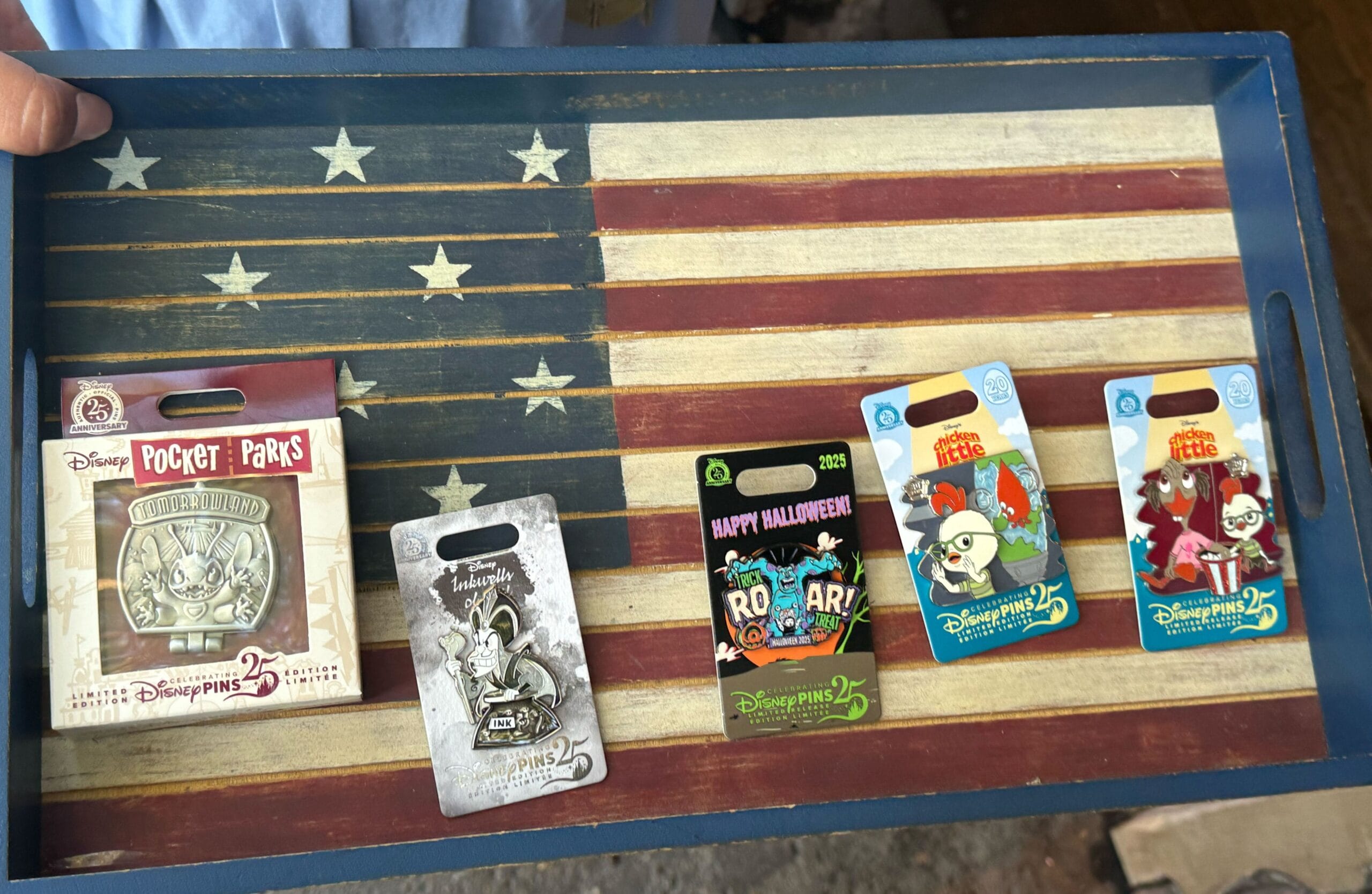 Five Disney pins on an American flag tray; Jafar Inkwells of Evil, Tomorrowland Stitch, all from Disney parks but no castles shown.