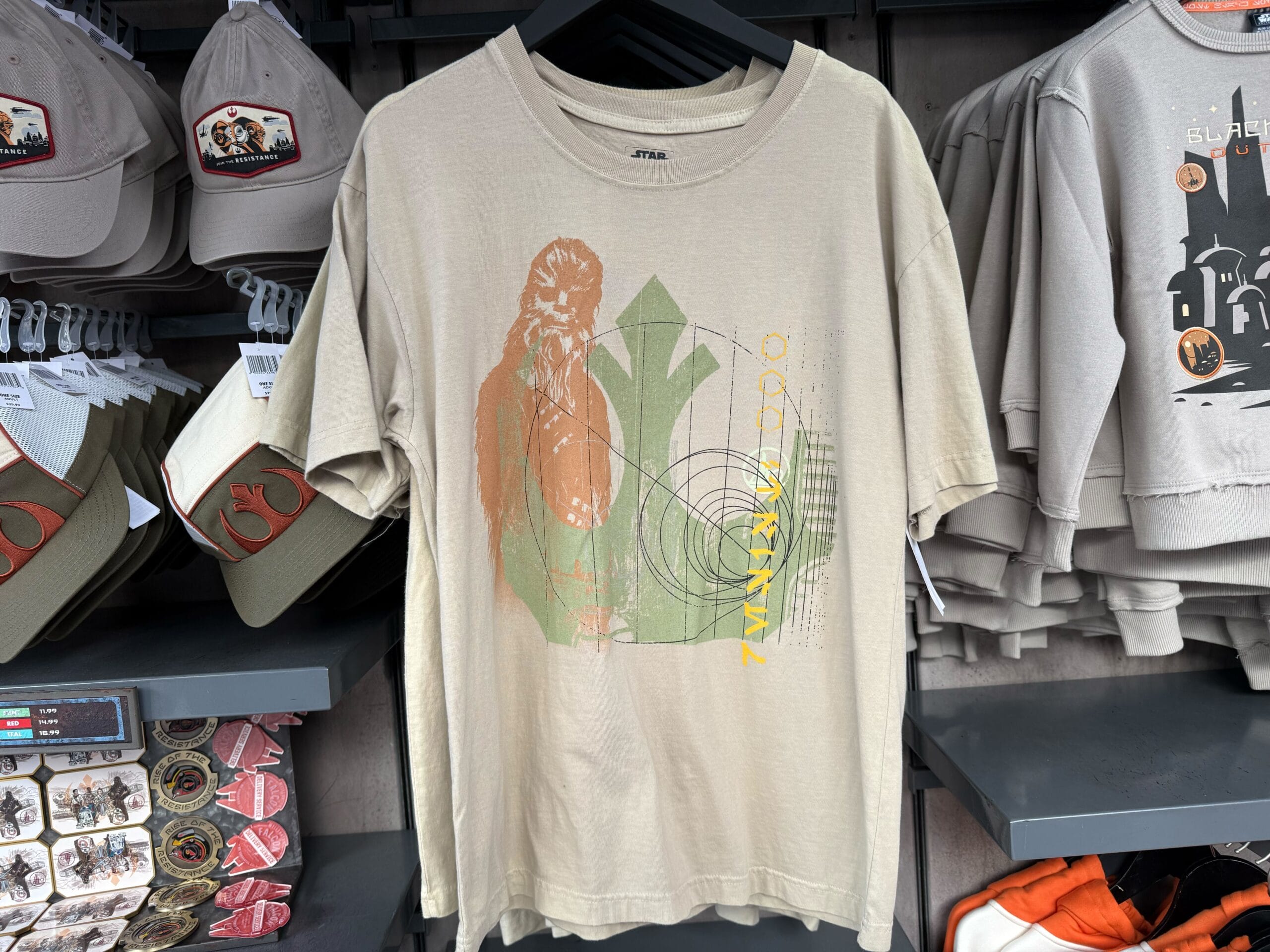 Beige tee with Chewbacca graphic, geometric shapes, and "CHEWBACCA" text, spotted at Star Wars: Galaxy’s Edge in Disney Parks.