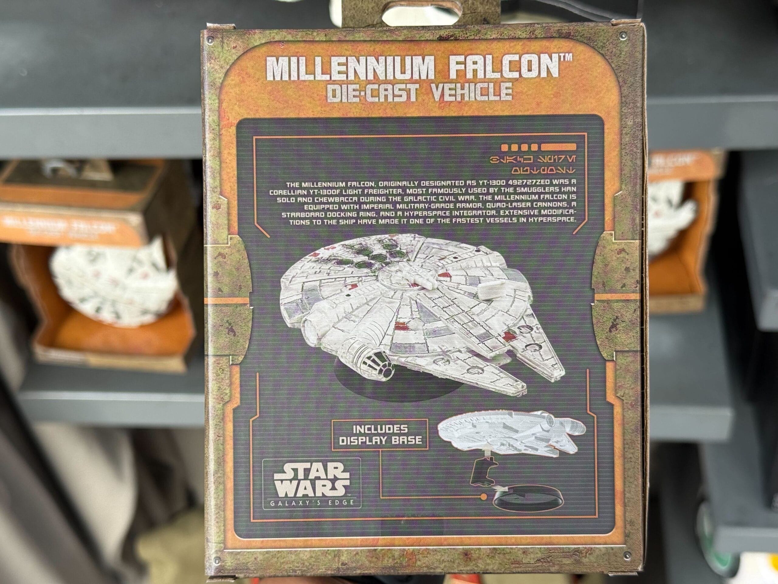 A die-cast Millennium Falcon toy on display in Galaxy’s Edge merchandise packaging at a Disney park, base included.