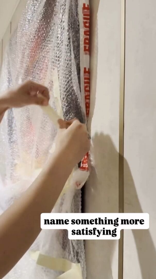 Hands peeling tape from bubble wrap on framed art labeled "FRAGILE"—almost as satisfying as spotting Cinderella Castle at Disney.