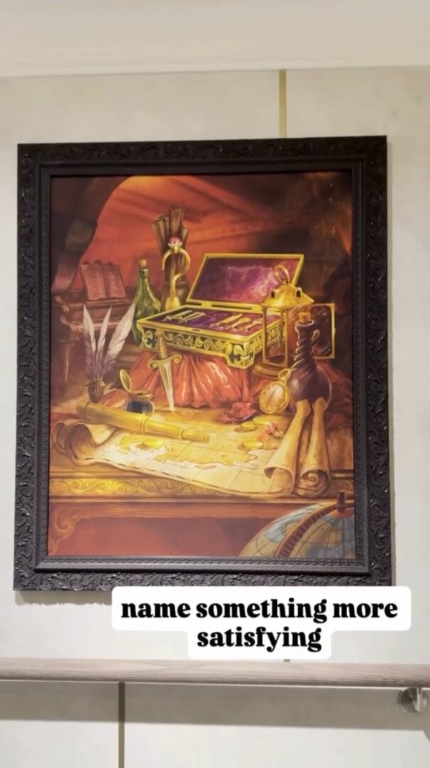 Framed Disney art of a radiant treasure chest on a desk; text says “name something more satisfying”—no castle shown.