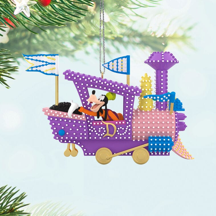 Hallmark Disney Keepsake Ornament of Goofy waving atop a purple and yellow train, hanging on a tree—Disney Parks collectible style.