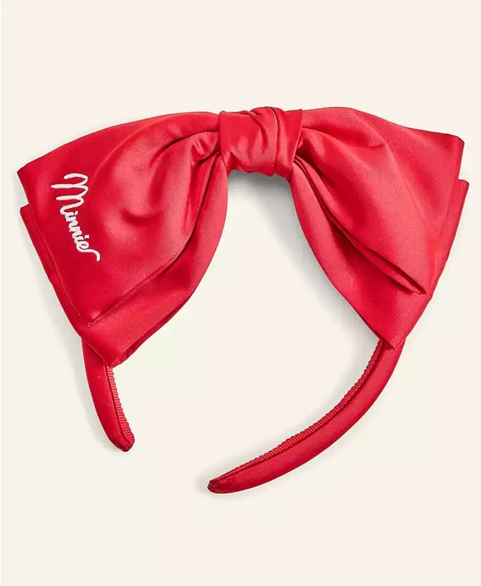Red Minnie Mouse headband with large satin bow and "Minnie" in white, from Macy's Holiday Collection, seen at a Disney Park.