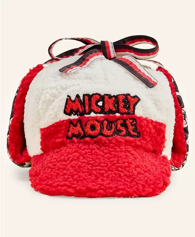 Red and white fuzzy cap from a Disney park’s 2025 Holiday Collection, “Mickey Mouse” text, floppy ear flaps, tied at the top.