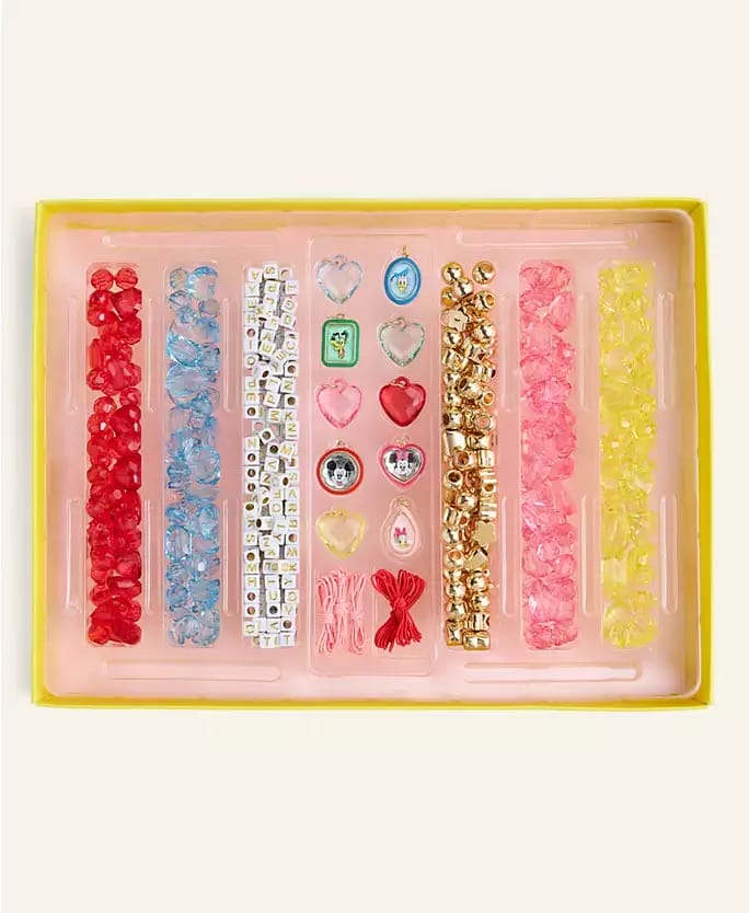 A Disney 2025 Holiday Collection jewelry kit with colorful beads, charms, and string, inspired by park-exclusive castle designs.