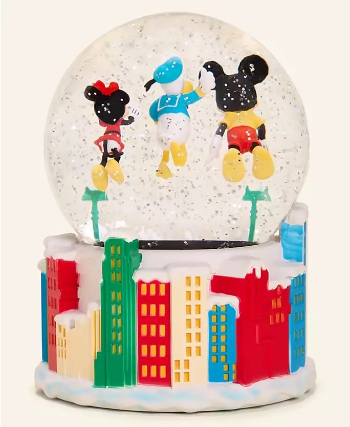 A Disney Parks snow globe featuring cartoon mice in winter gear over city buildings, from the 2025 Holiday Collection. No castle present.