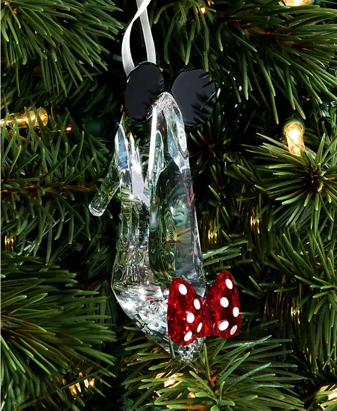 A glass slipper ornament from the Disney 2025 Holiday Collection sparkles on a Christmas tree, reminiscent of Cinderella Castle.