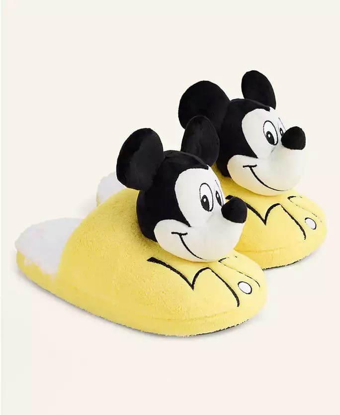 Yellow slippers shaped like Mickey Mouse heads from the Disney 2025 Holiday Collection, spotted at a Disney park gift shop.