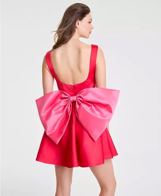 Woman in a red backless dress with a pink bow, Macy's 2025 Holiday Collection, faces away—no Disney castle in view to compare.