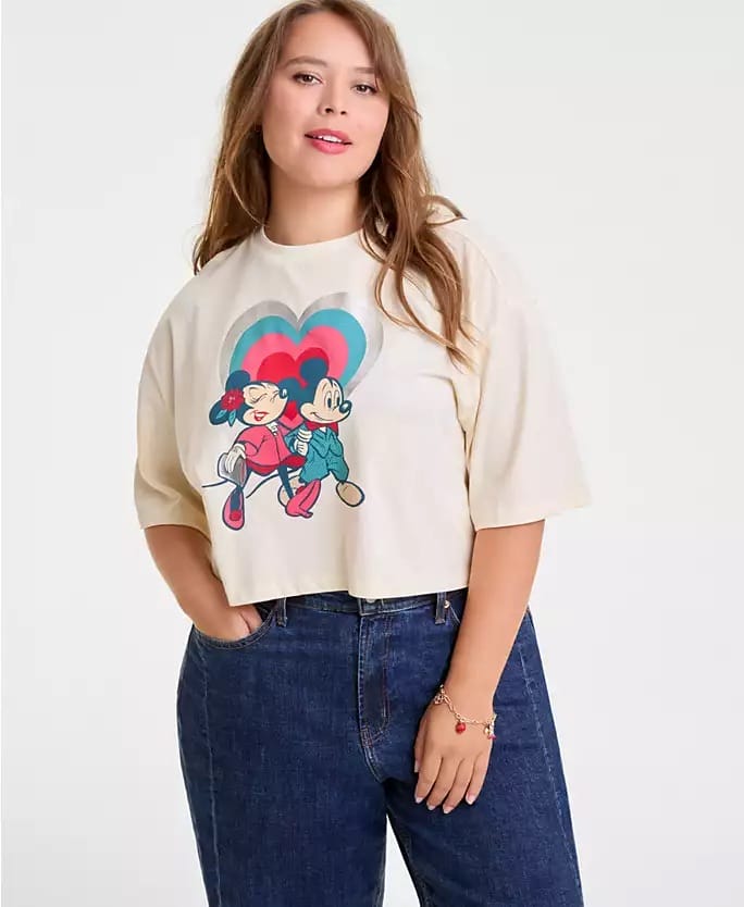 Woman in a cream Disney cropped T-shirt and blue jeans, Holiday Collection at Macy’s. No castle shown for park comparison.