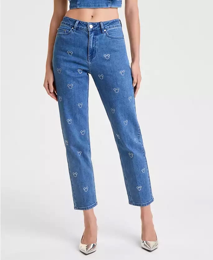 Woman in Disney Holiday Collection blue jeans with white Mickey Mouse heads, silver heels; reminiscent of Disney Parks festive style.