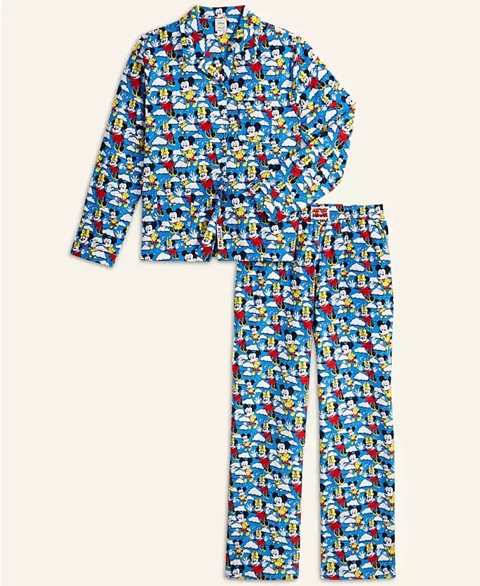 Blue pajama set with Disney cartoon print from the 2025 Holiday Collection, displayed near iconic Disneyland castle architecture.