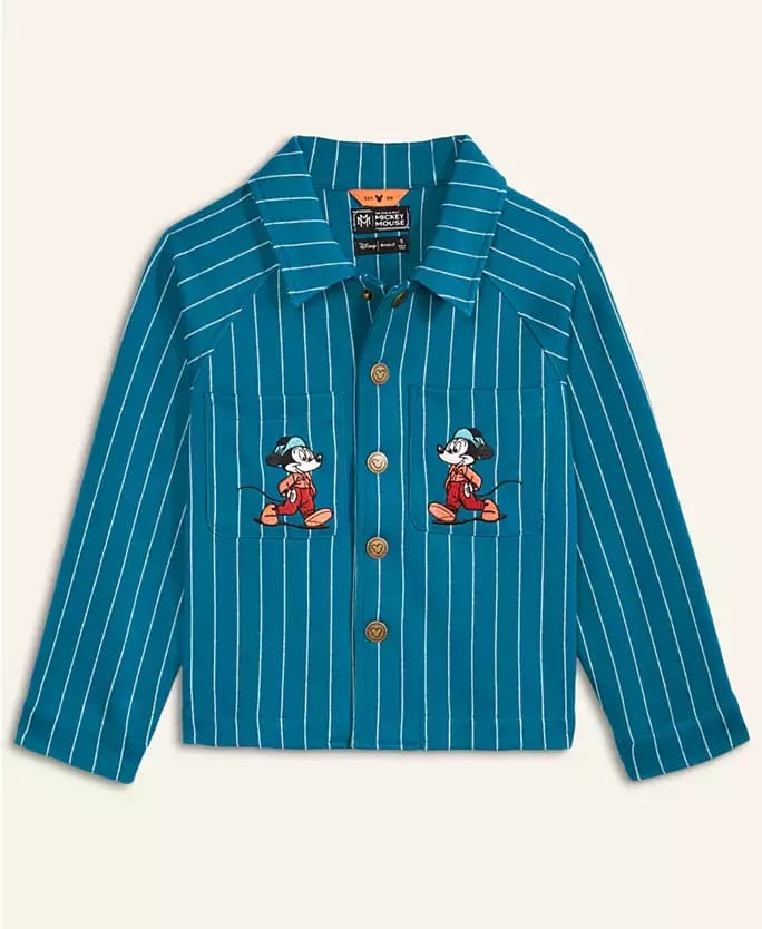 Blue pinstripe kids' shirt with Mickey Mouse patches, from the Disney 2025 Holiday Collection, seen in a Disney park setting.