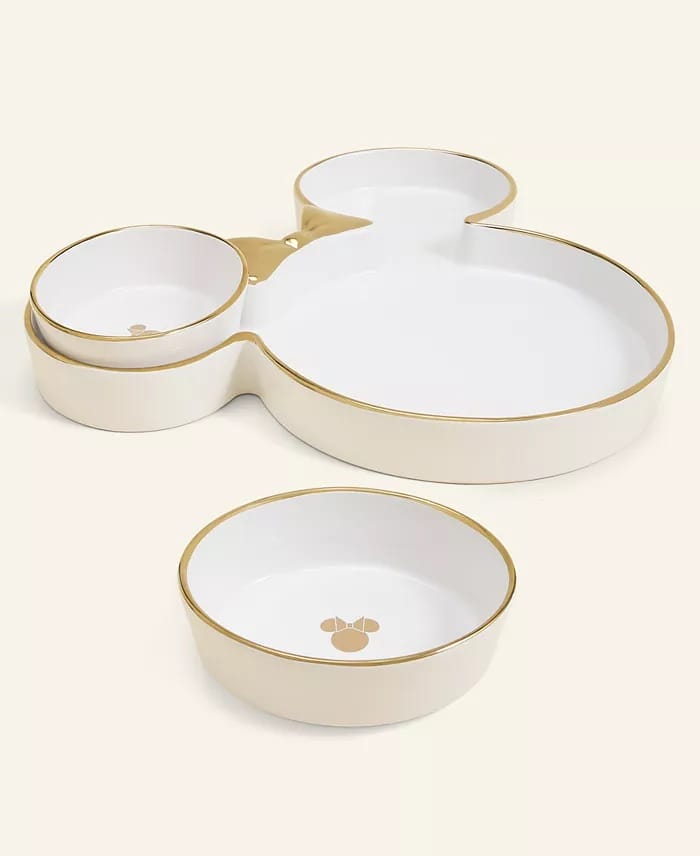 Four cream and gold Mickey plates, echoing Disney park elegance, with one plate featuring a small icon from the 2025 Holiday Collection.
