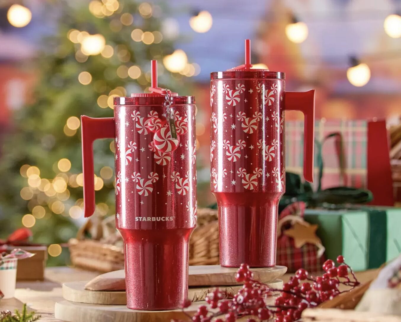 Two red Starbucks tumblers with Peppermint Swirl designs sit on a table, festive decor evoking Main Street USA’s holiday charm.