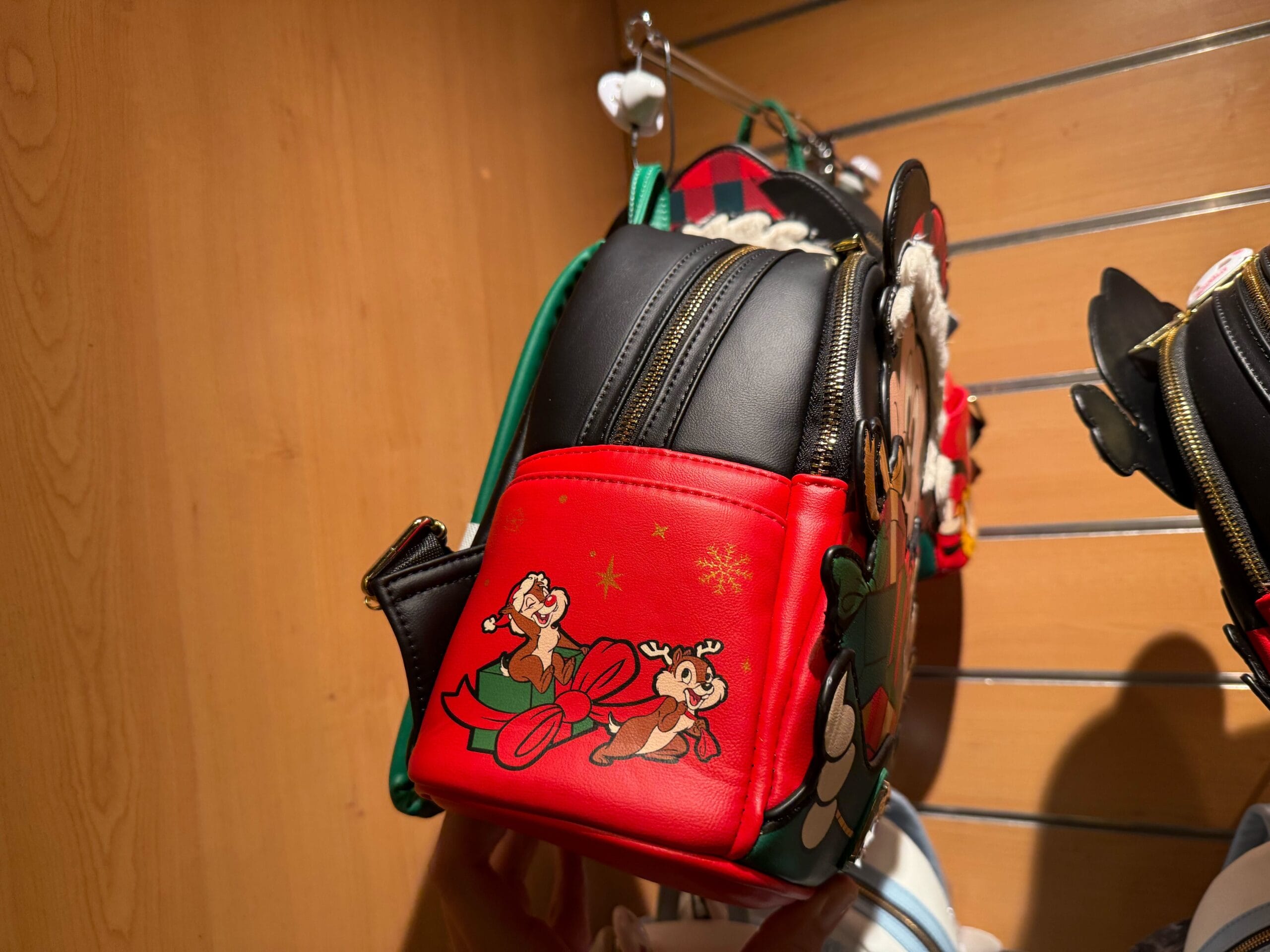 A festive Christmas Loungefly backpack featuring Disney’s Chip and Dale sledding, with snowflakes, from Disneyland Paris.